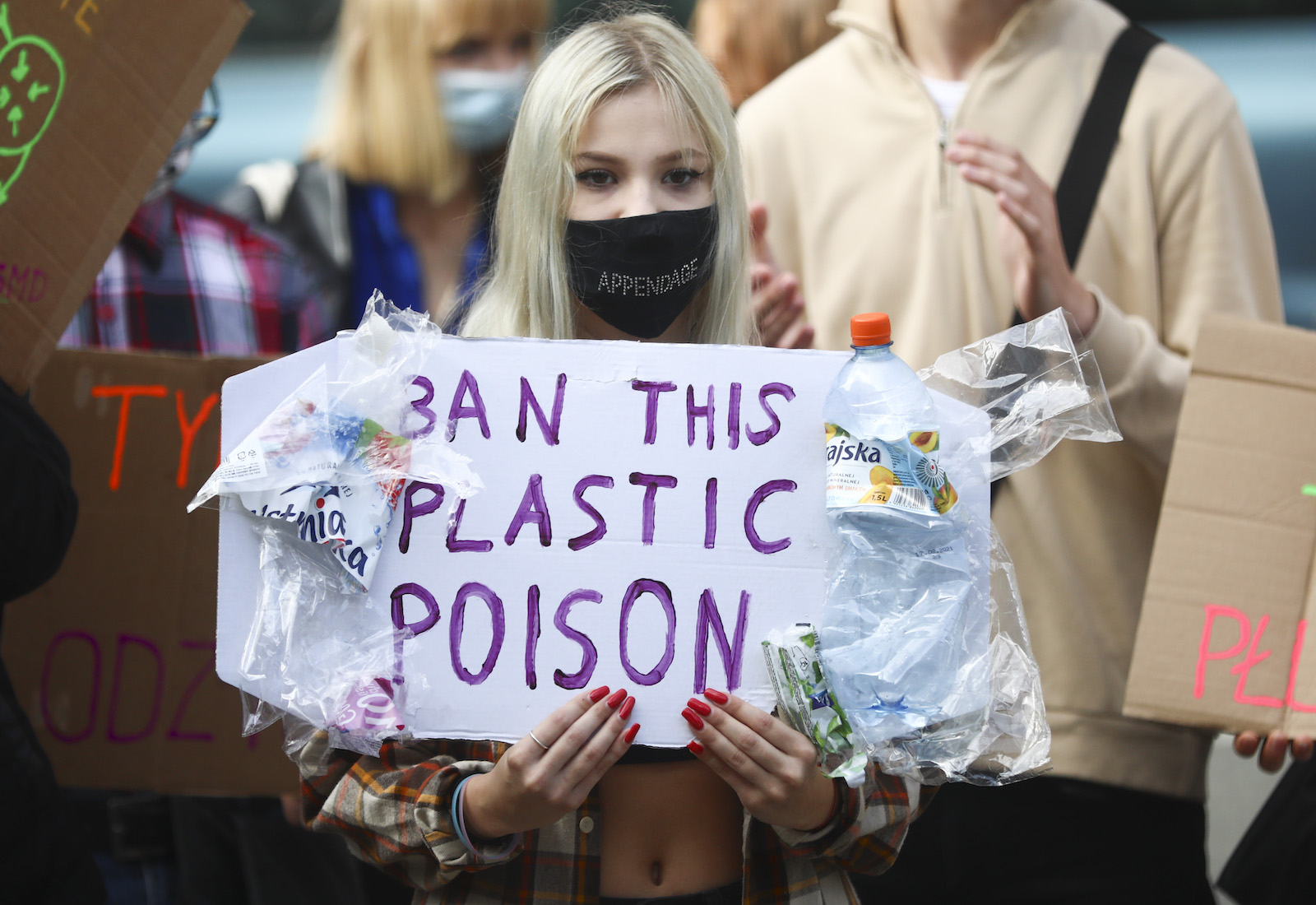 A protester holds a sign reading, "ban this plastic poison"
