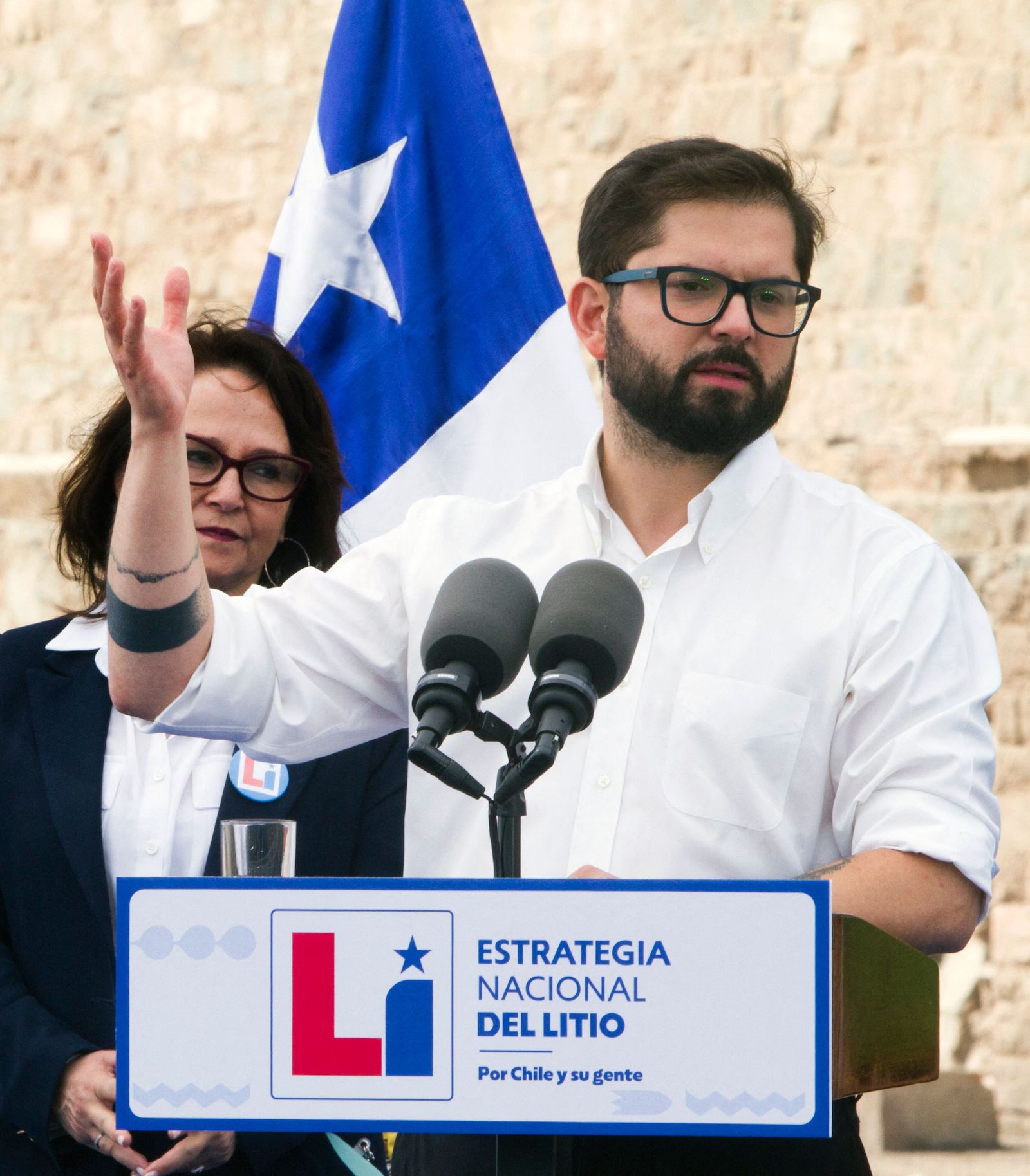 Chile's President Gabriel Boric speaking at a podium with the Chilean flag in the background