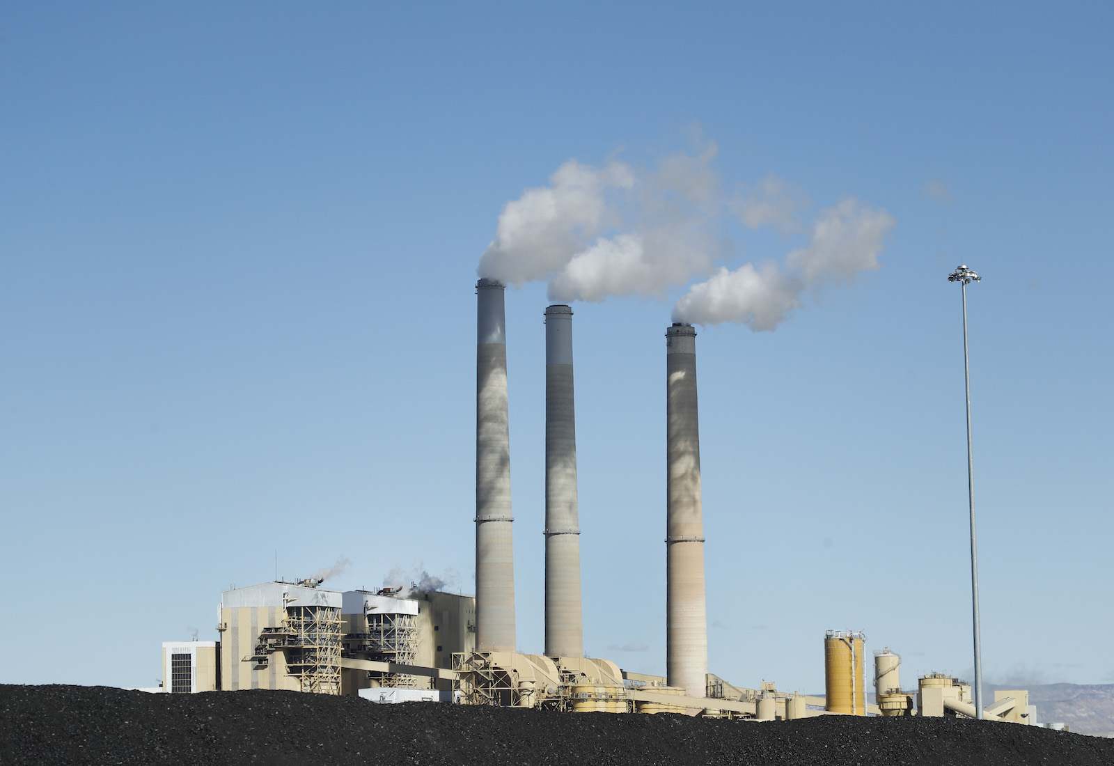 A coal plant with smokestacks blowing smoke