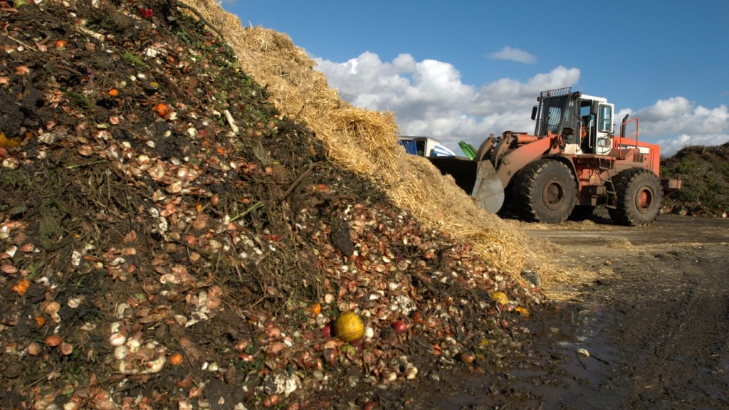 A tractor approaches garden waste at a compost center in England