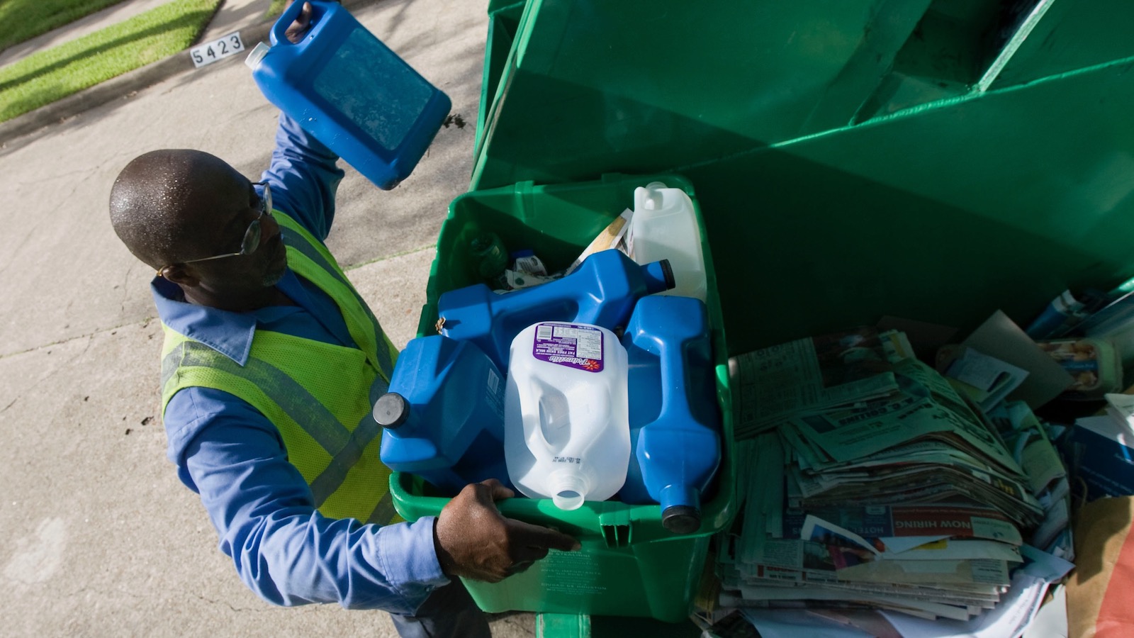 A city employee tosses an assortment of plastic containers into a curbside recycling truck in Houston, Texas.