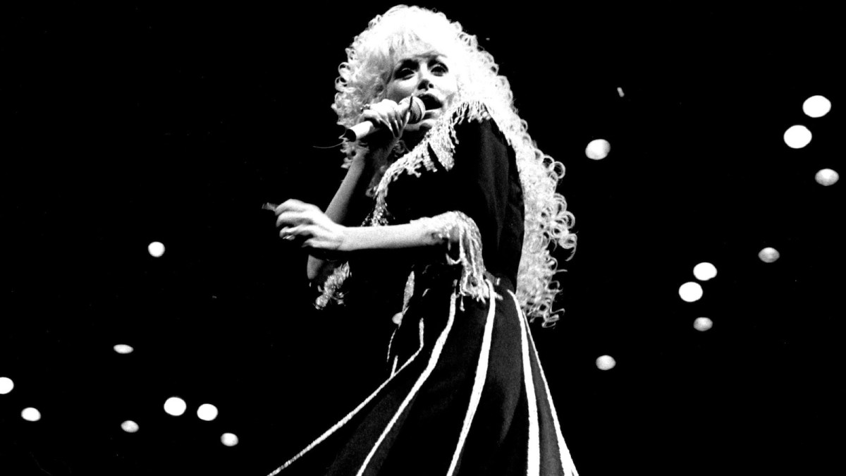 Country singer Dolly Parton appears in a black and white photo showing her performing in concert on a darkened stage at the Sydney Entertainment Centre.
