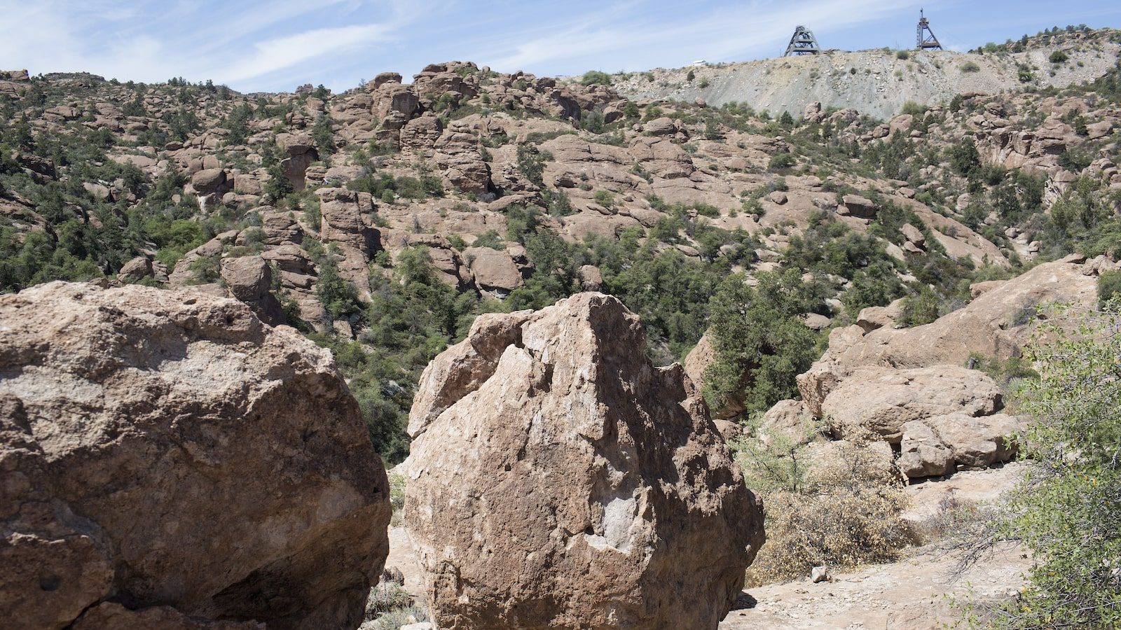 a large rock sits in a desert landscape near metal scaffolds
