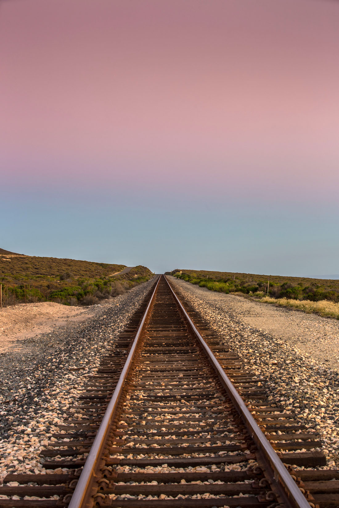 railroad tracks near sand at sunset