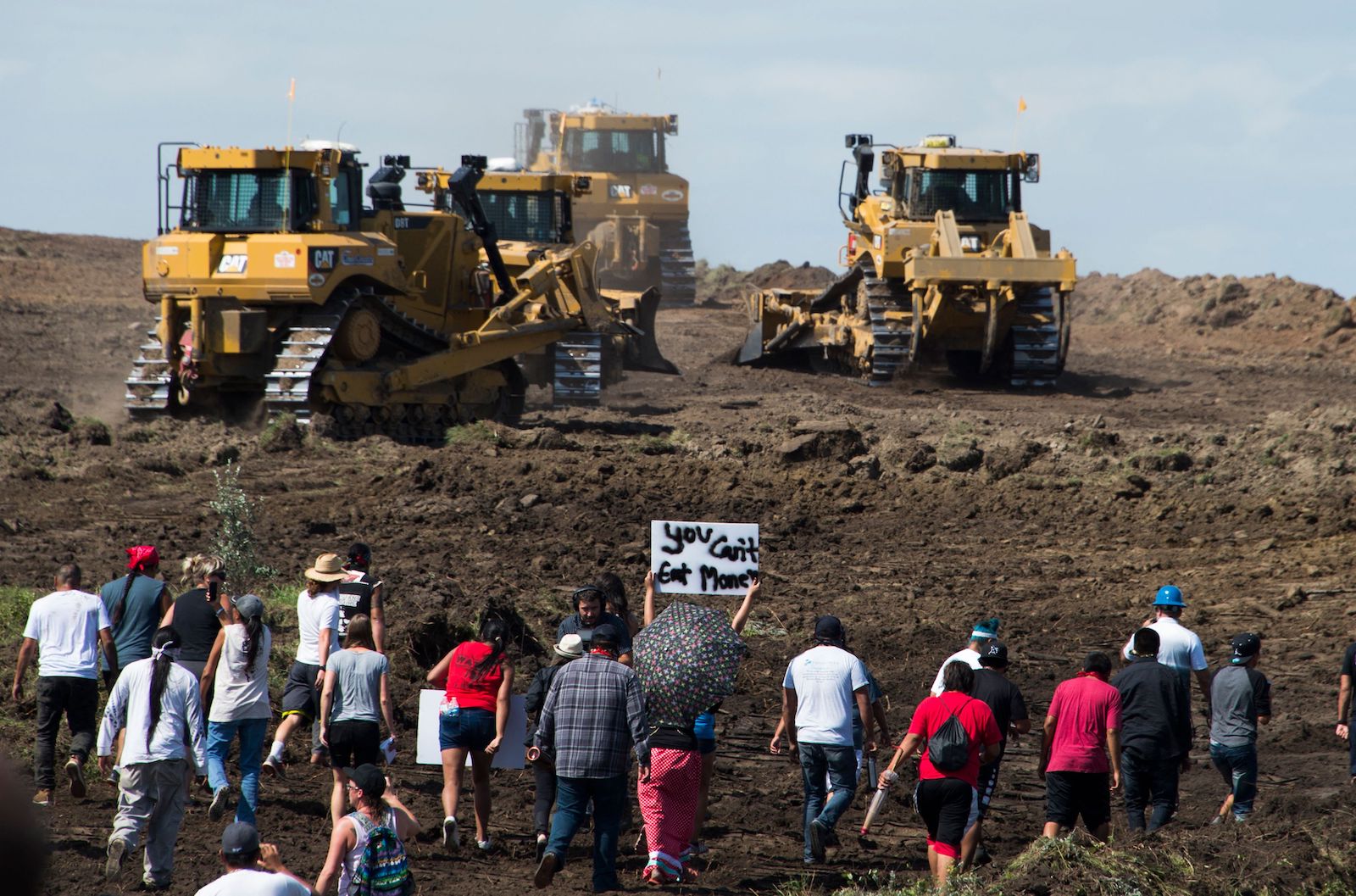 a group of people hold signs near bulldozers