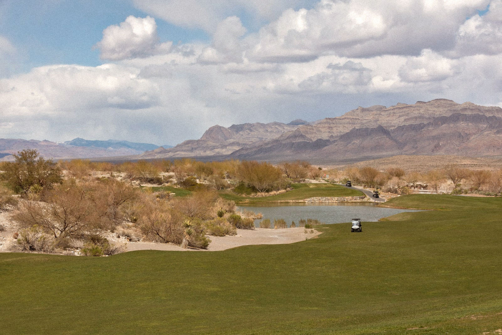 a golf course green next to dry mountains