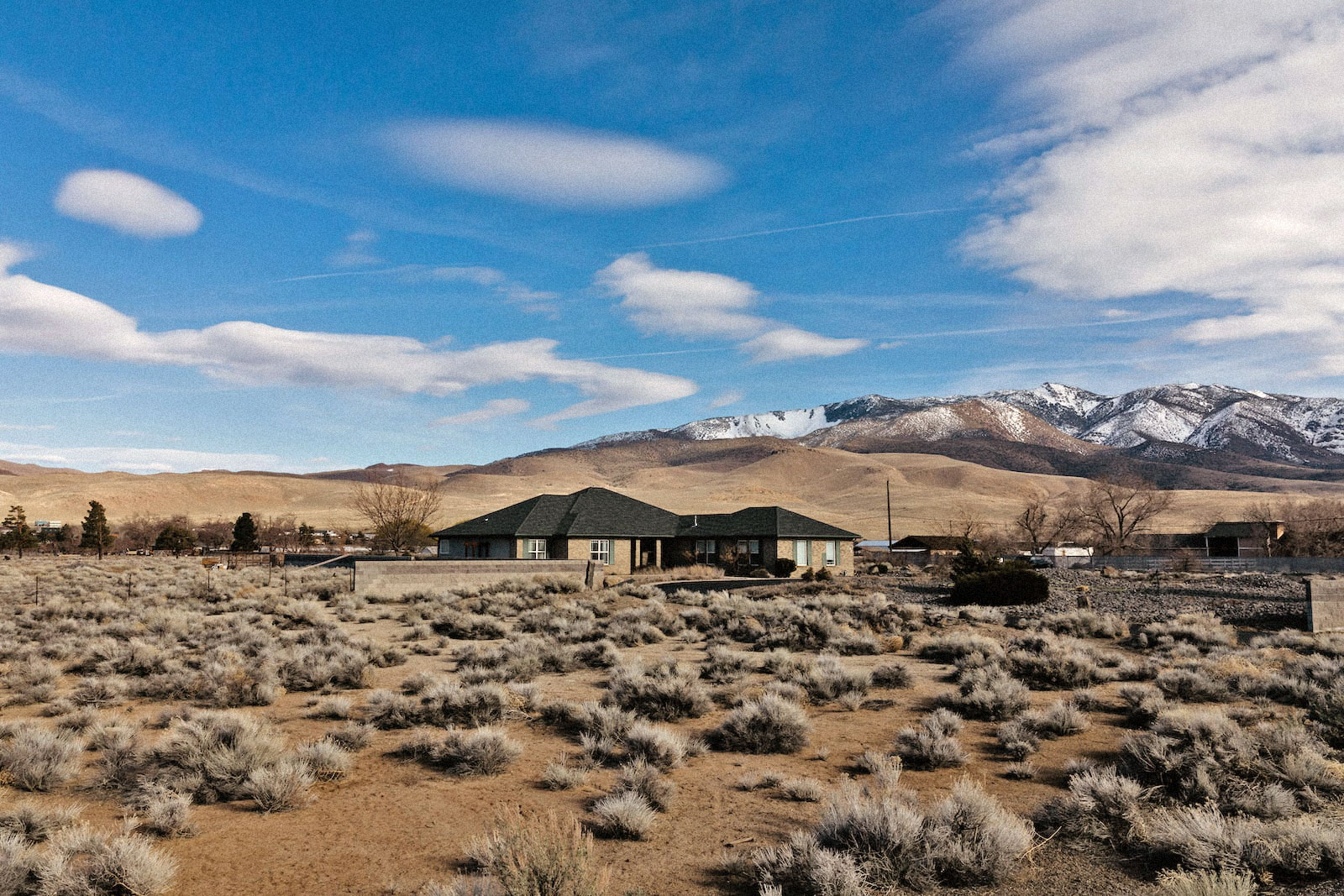 a ranch-style house in the middle of a dry landscape