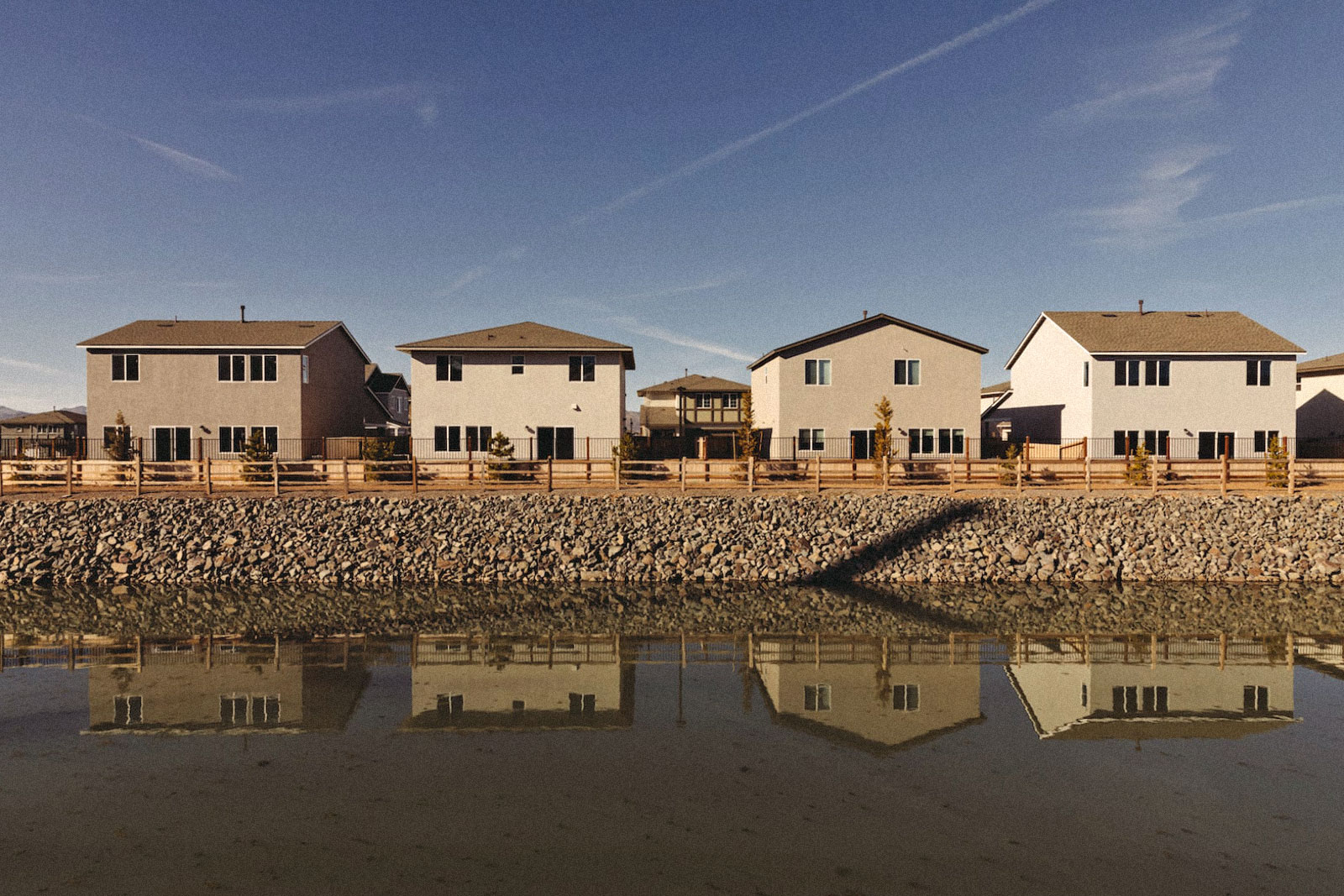 a line of four houses reflected into a body of water