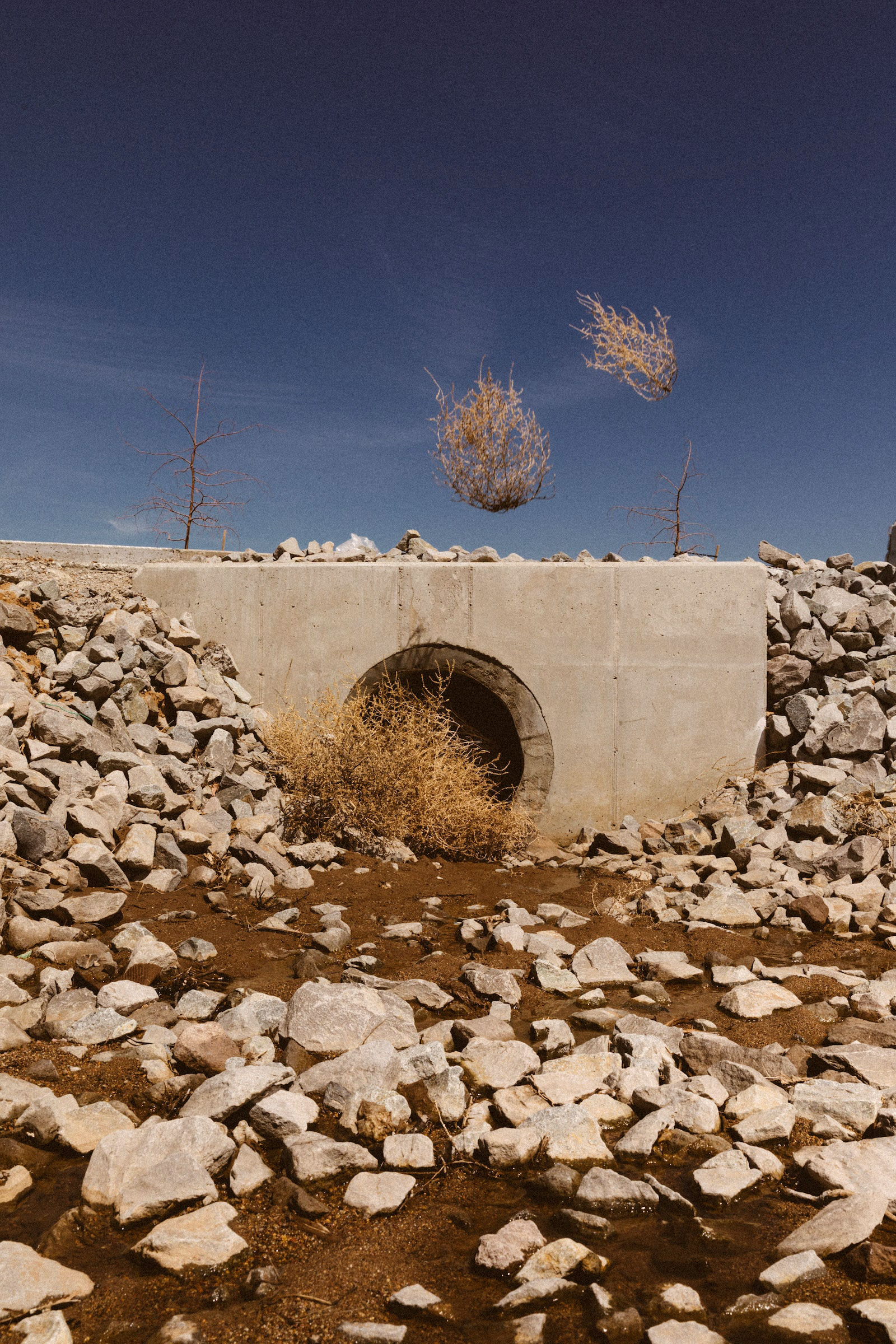 tumbleweeds fly over a concrete arch with a hole in the center