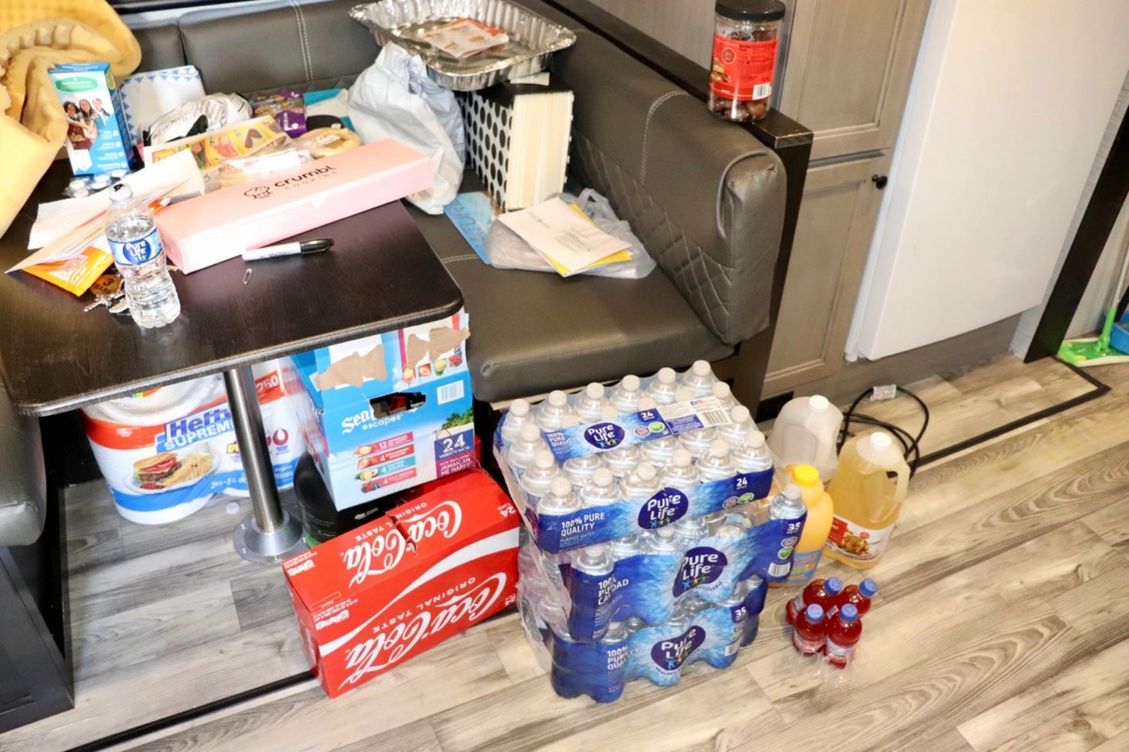 Stacks of bottled water and Coke sit on the floor of a room.
