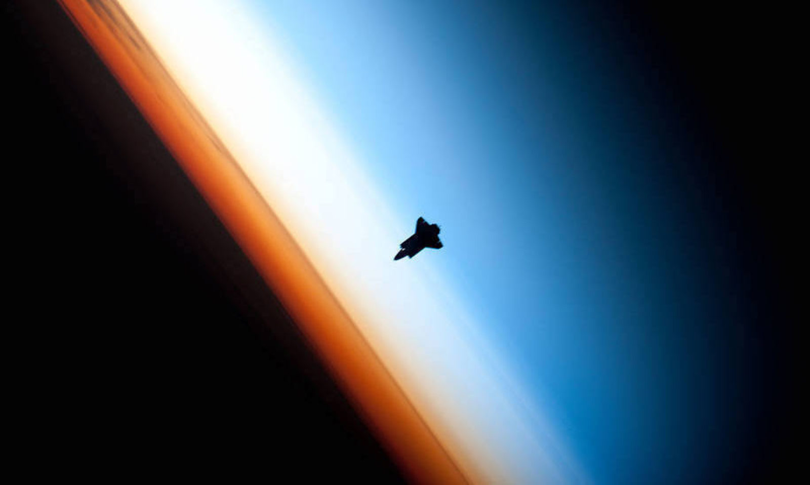 A photo of a rocket in space floating between blue, white and orange layers of atmopshere.
