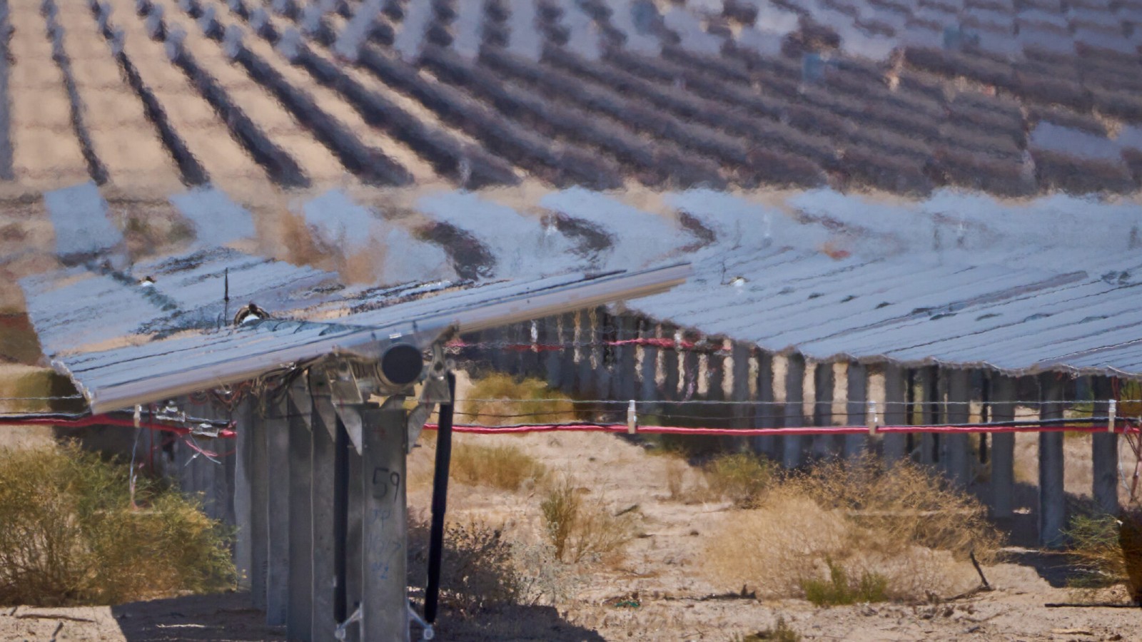 A hazy field of solar panels pointing at the sky in the desert.