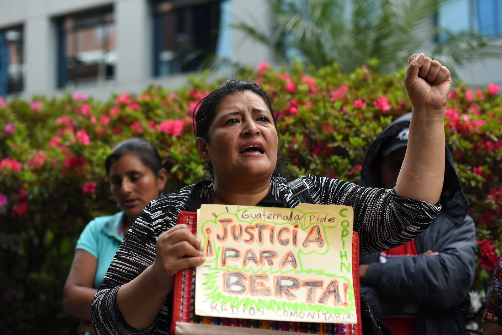 a woman holds a sign justicia para berta