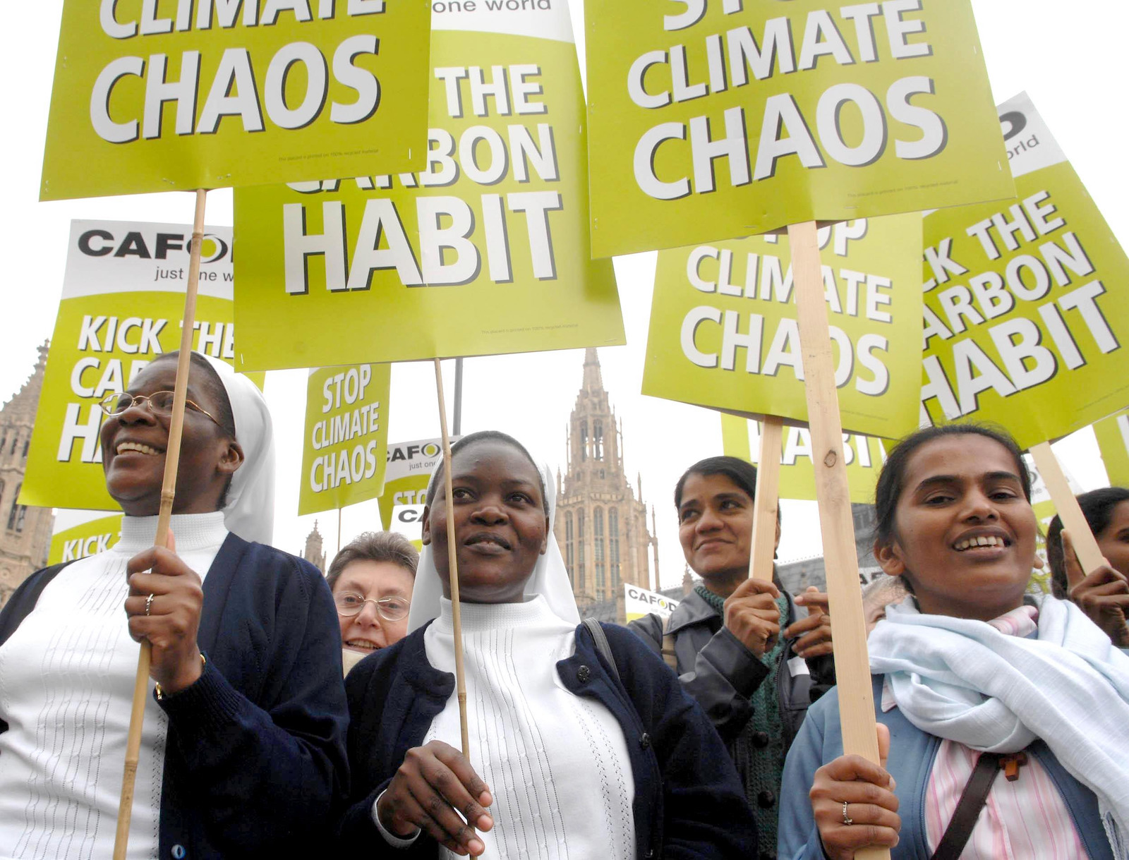 a group of nuns hold protest signs in support of climate action