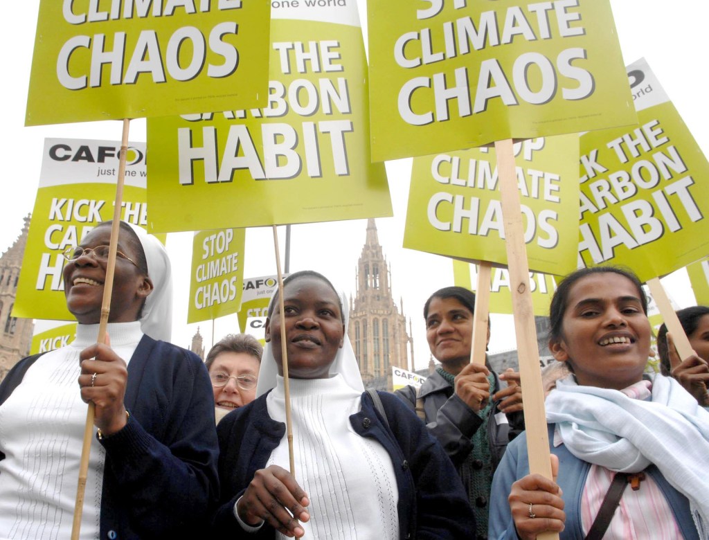 a group of nuns hold protest signs in support of climate action