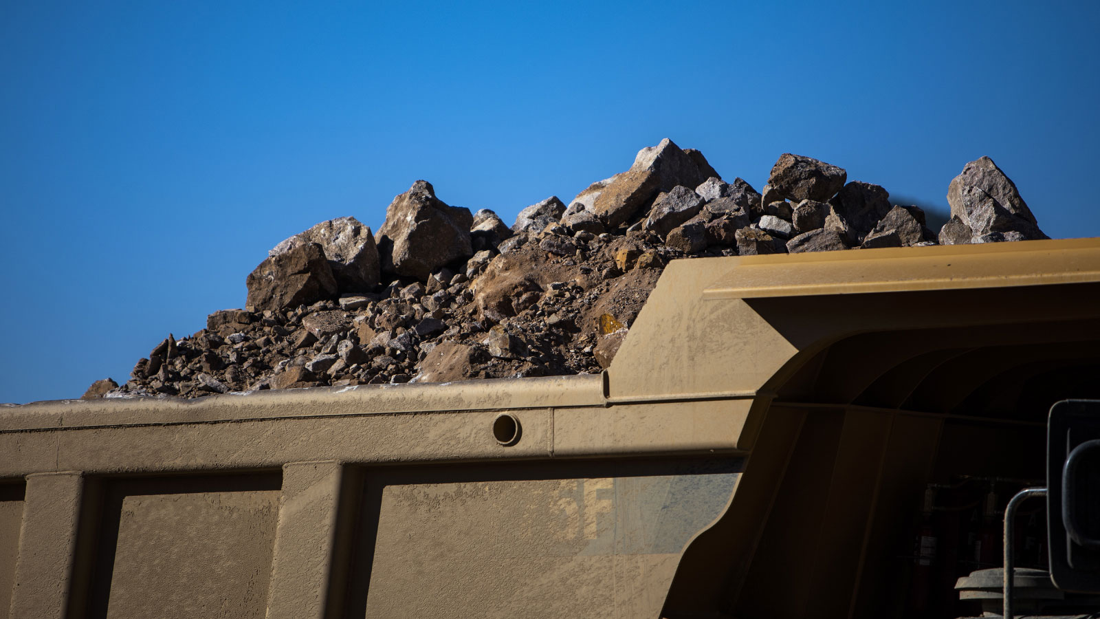 a truck carrying rocks against a blue sky