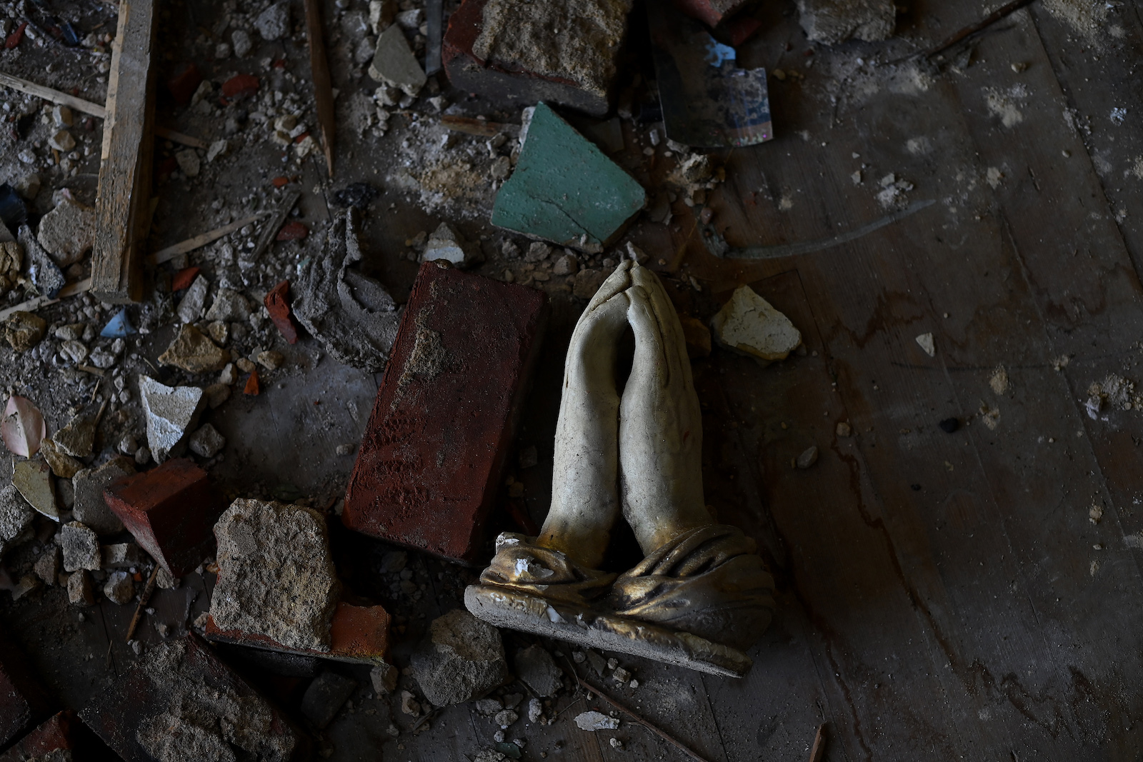 a statue of praying hands in a burned pile of objects