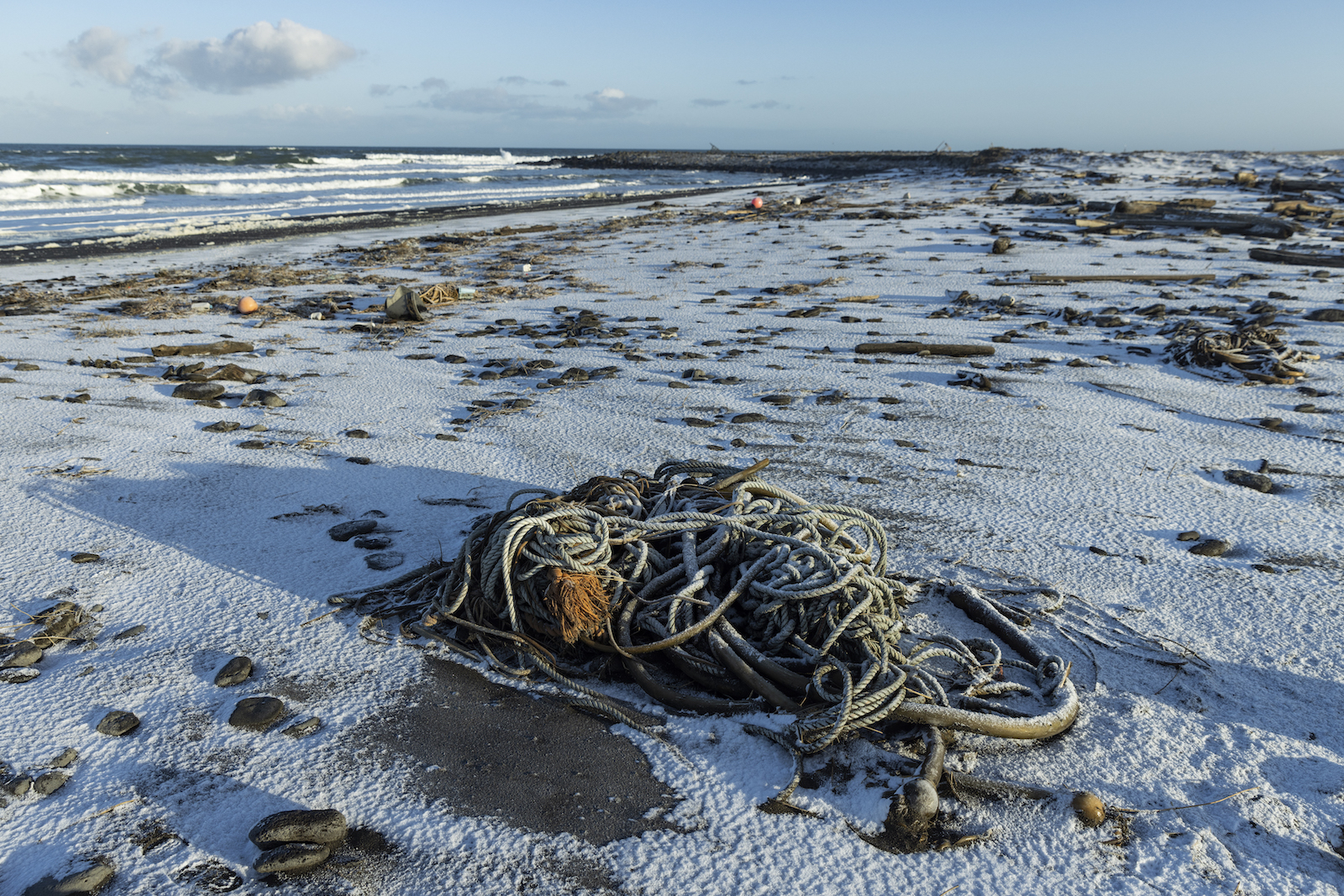 Marine debris sits on a snow-covered beach