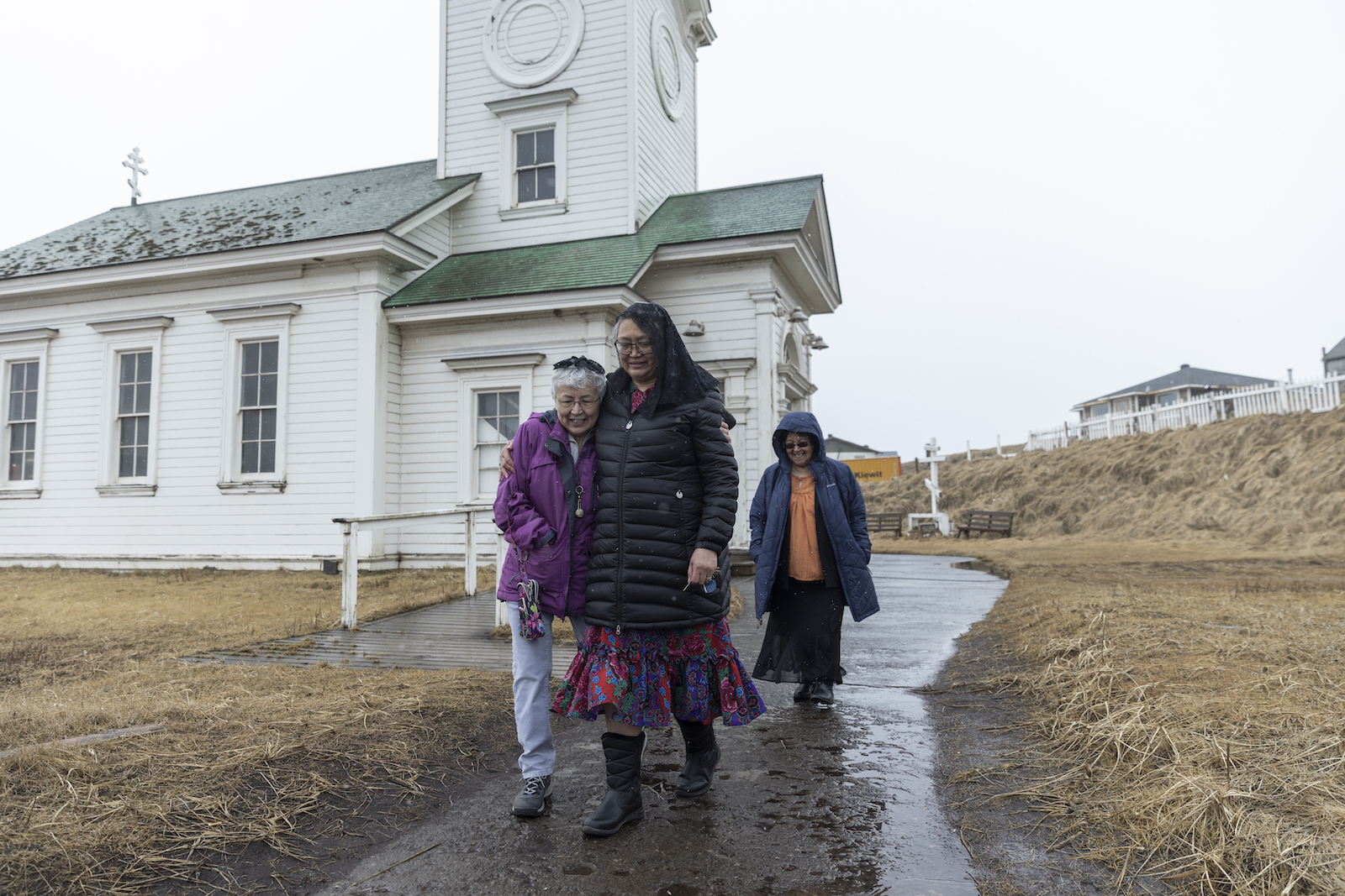 Three women walk away from a small white church
