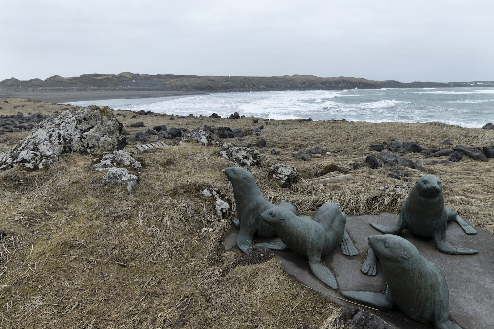 A statue on the beach depicts three seals