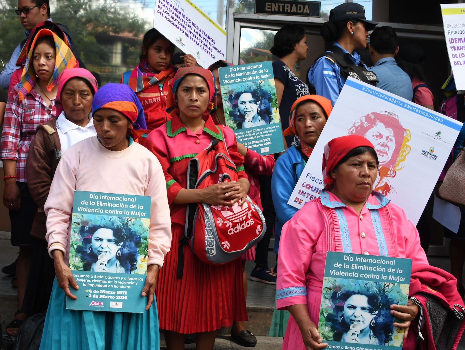 women hold signs showing a woman's face