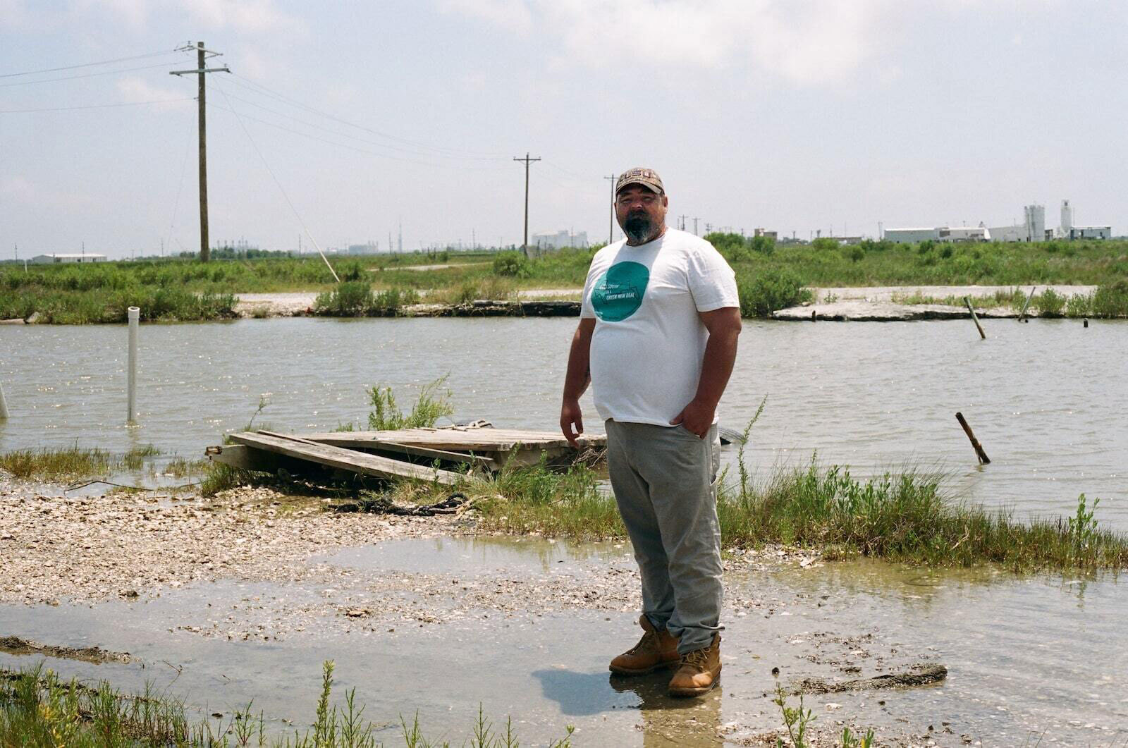 A man in a baseball cap and t-shirt in front of a river