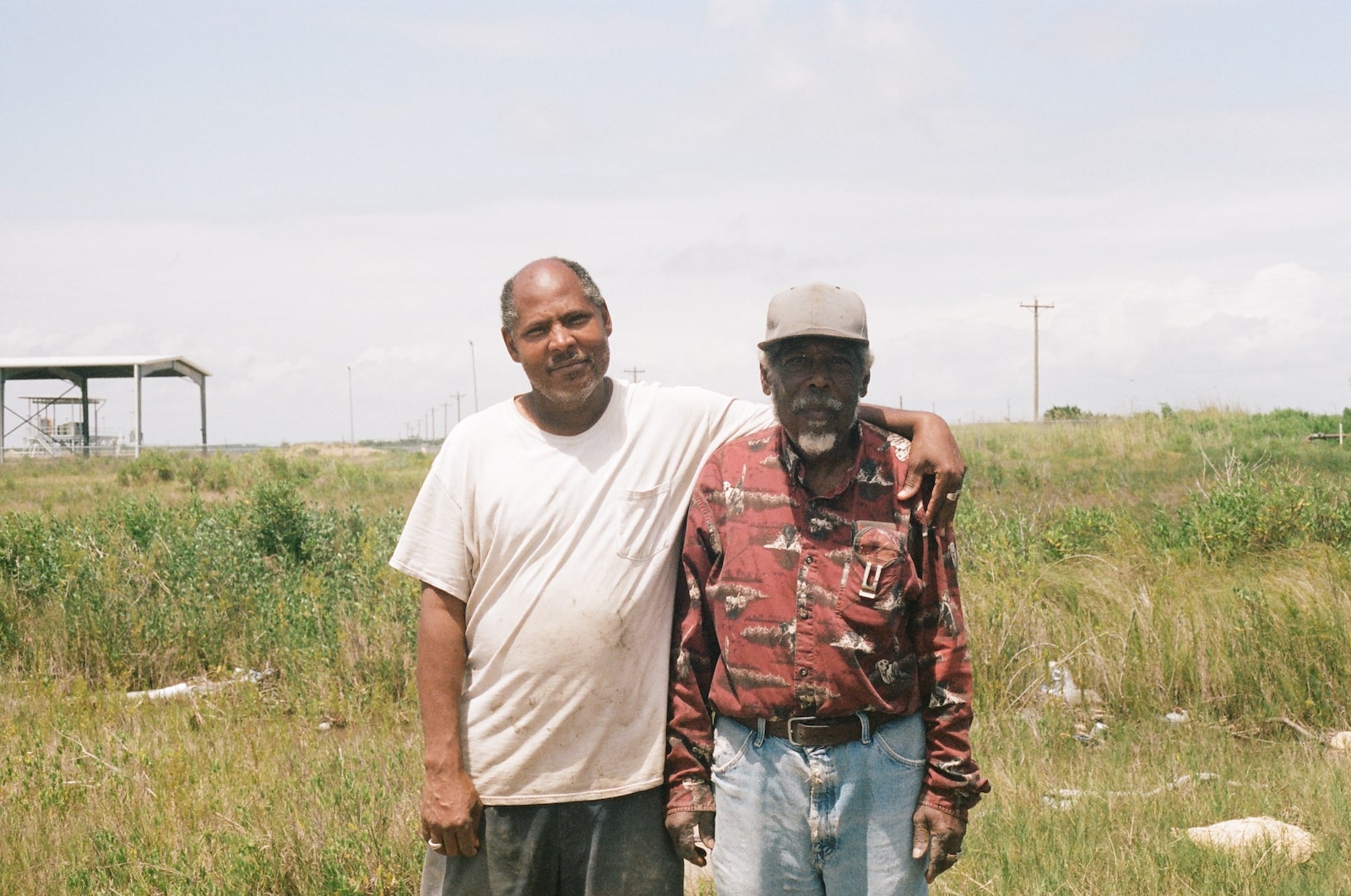 two men stand near green marsh