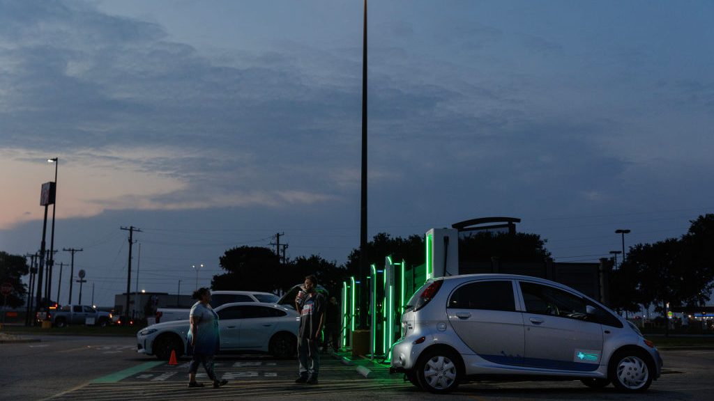 Two people stand near car at charging station