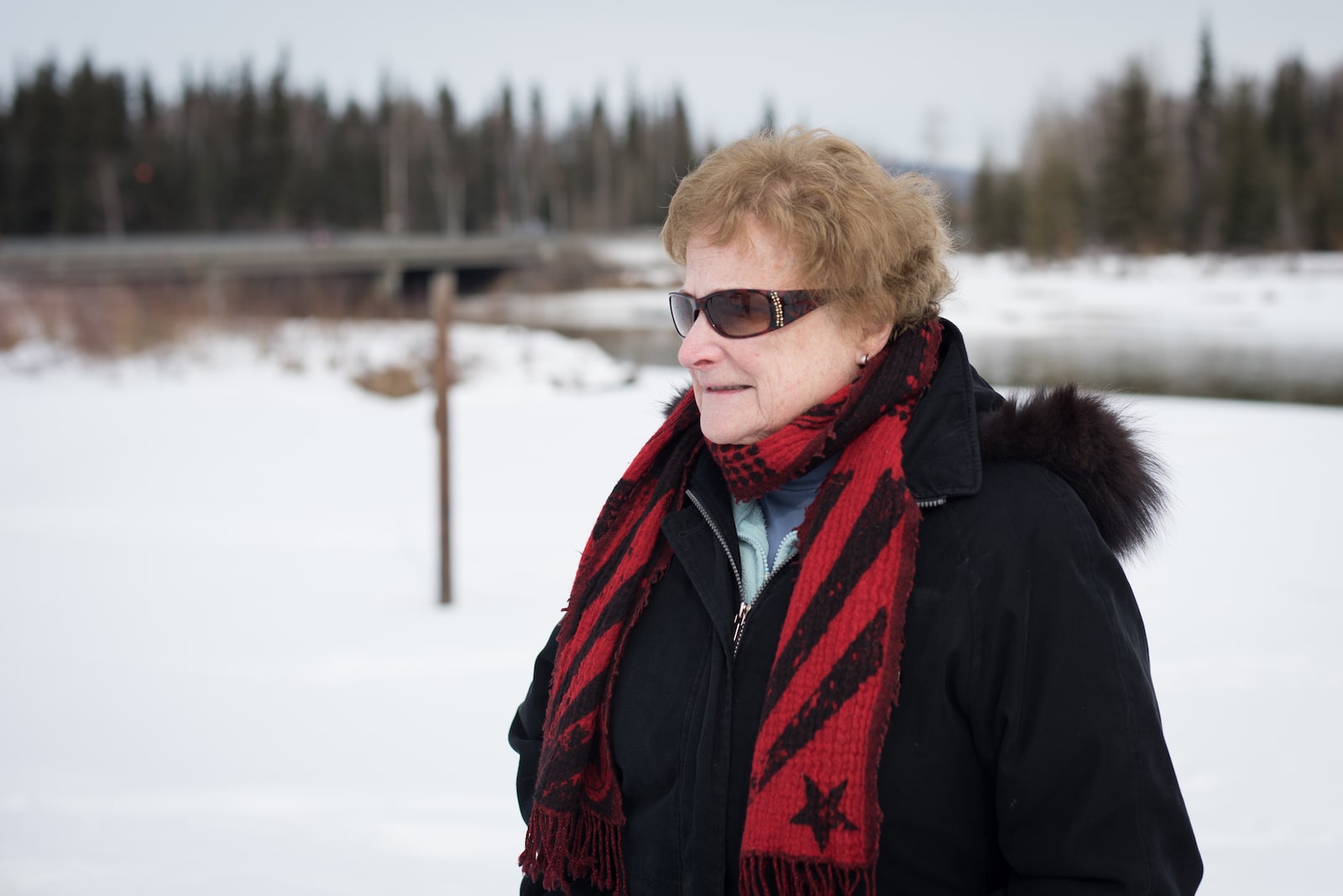 a woman in a red scarf and sunglasses on a snowy day