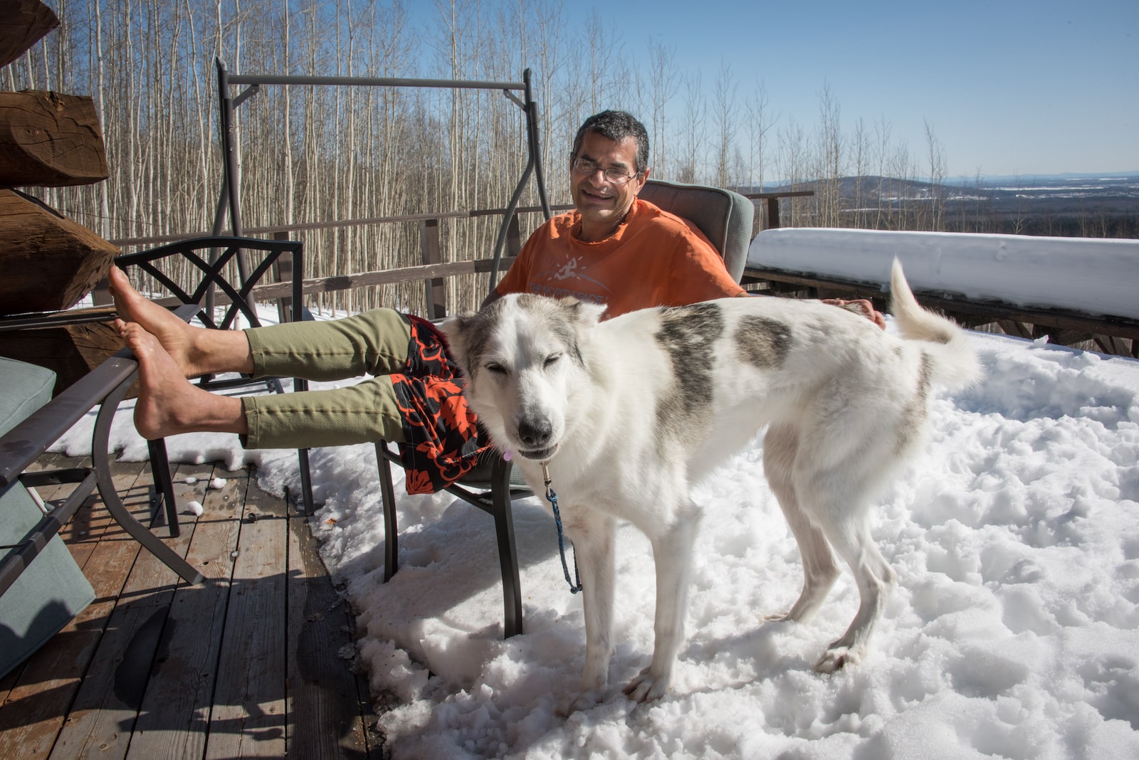 a man holds a furry white and gray dog