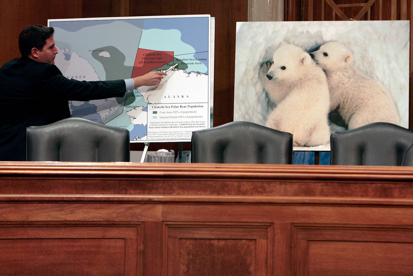 a man points to a mpa of alaska next to a picture of polar bears