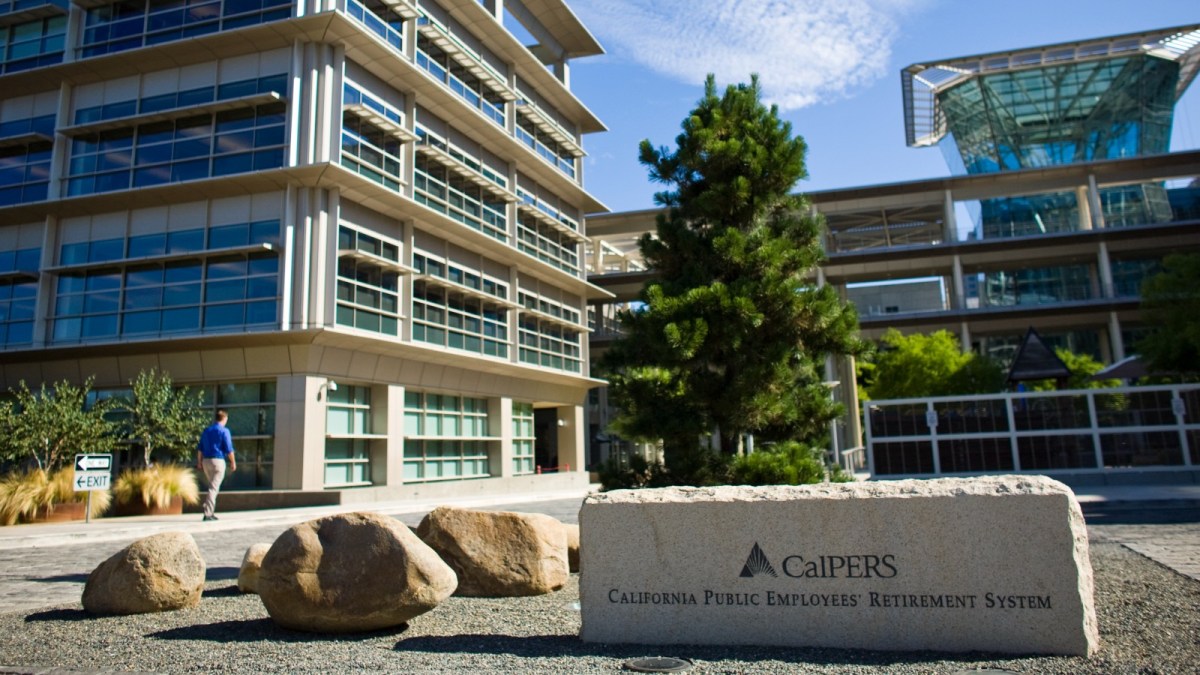 A stone sign that reads CalPERS in front of an office building and tree.