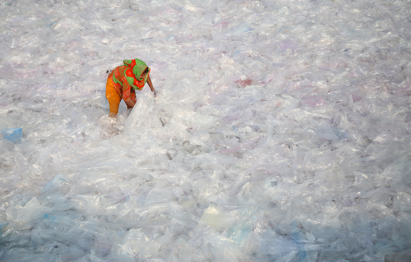 a woman sorts through a sea of plastic bags