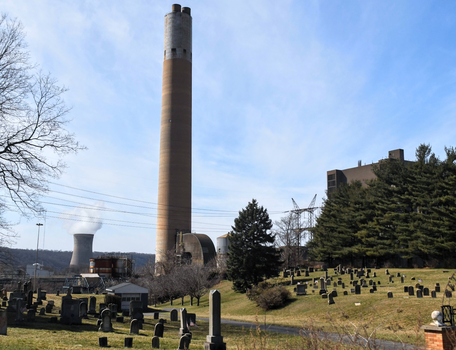 Two smokestacks tower over a graveyard.