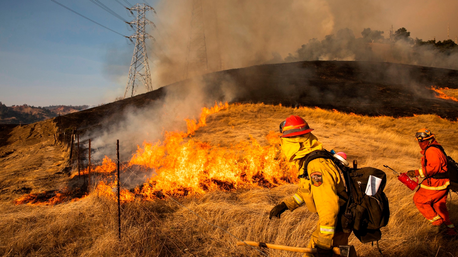 A back fire set by fire fighters burns a hillside near PG&E power lines during the 2019 Kincade Fire in Healdsburg, California.