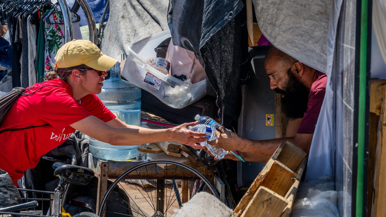 A volunteer hands out water to a person experiencing homelessness in Phoenix, Arizona, during a relentless, record-breaking heat wave in July 2023.
