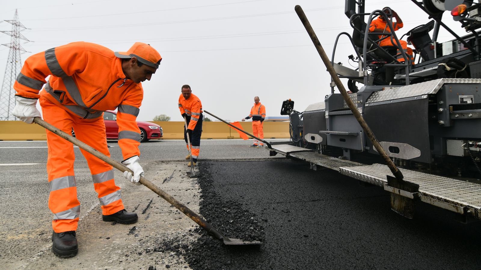 Workers lay down plastic-infused asphalt