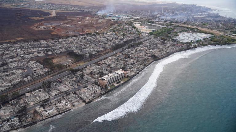 an aerial photo of the coast and burned out shells of buildings