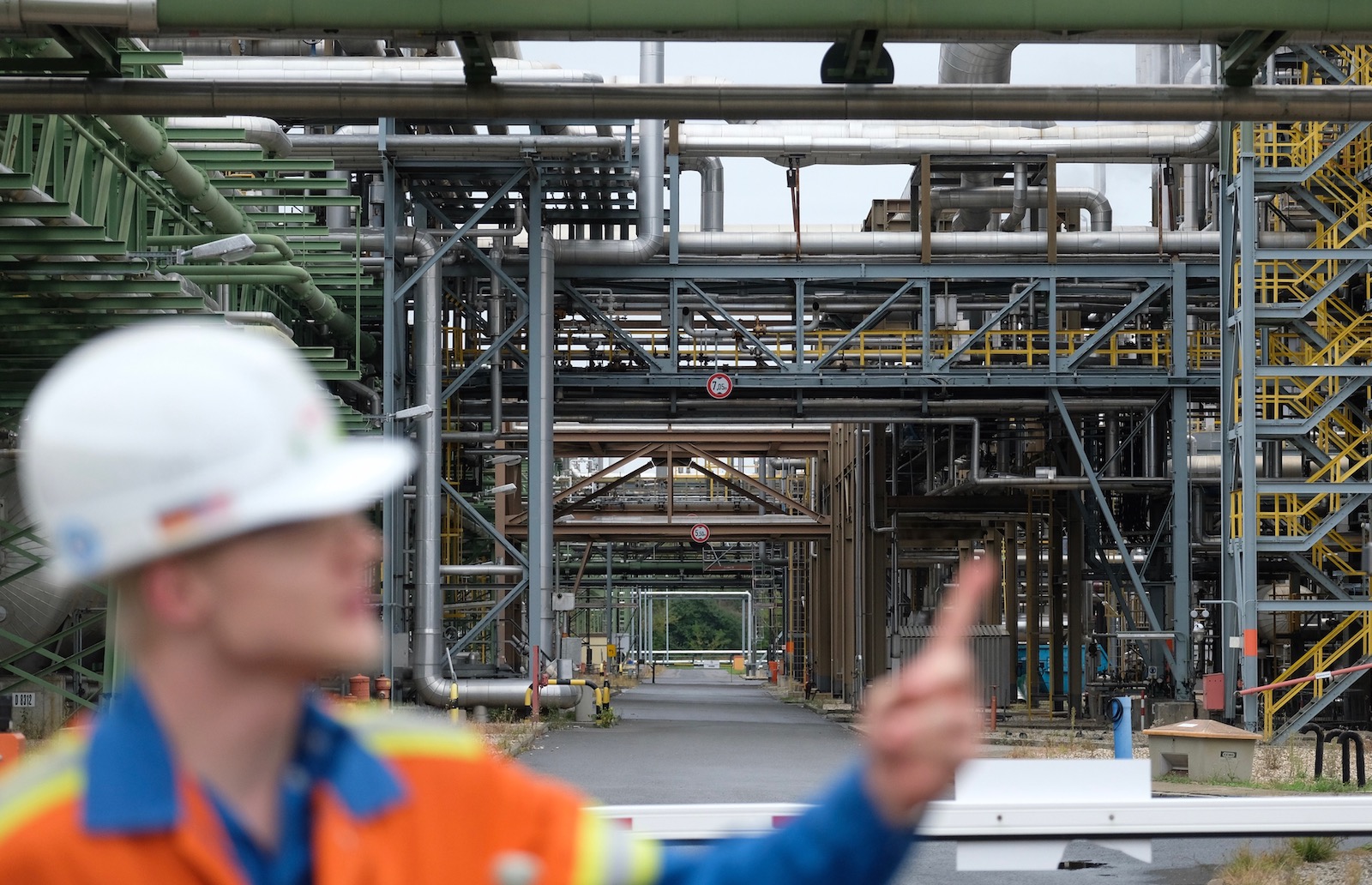 a man in a hard hat points at an industrial chemical plant