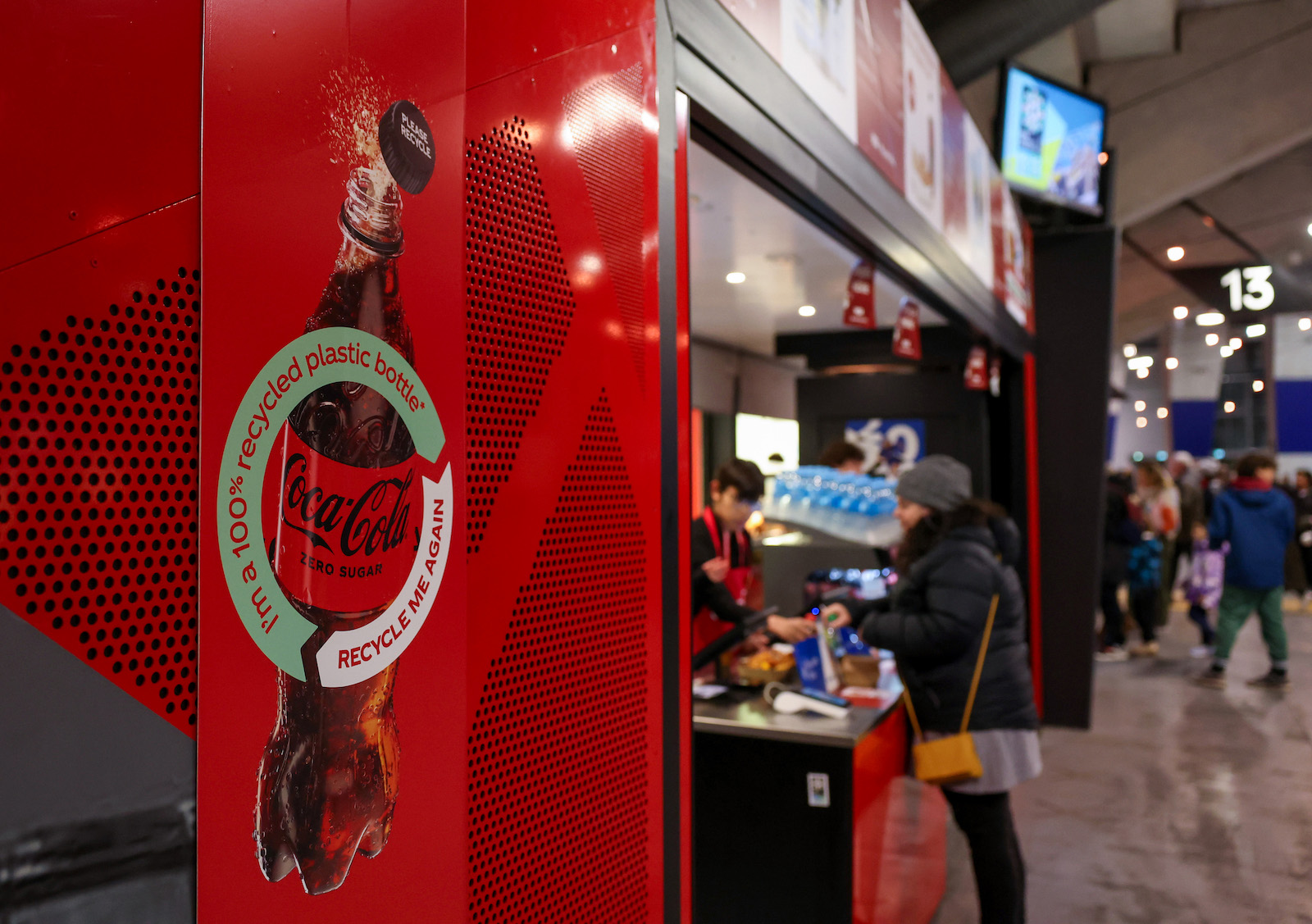 a red stand with a coca cola bottle and recycled plastic ad
