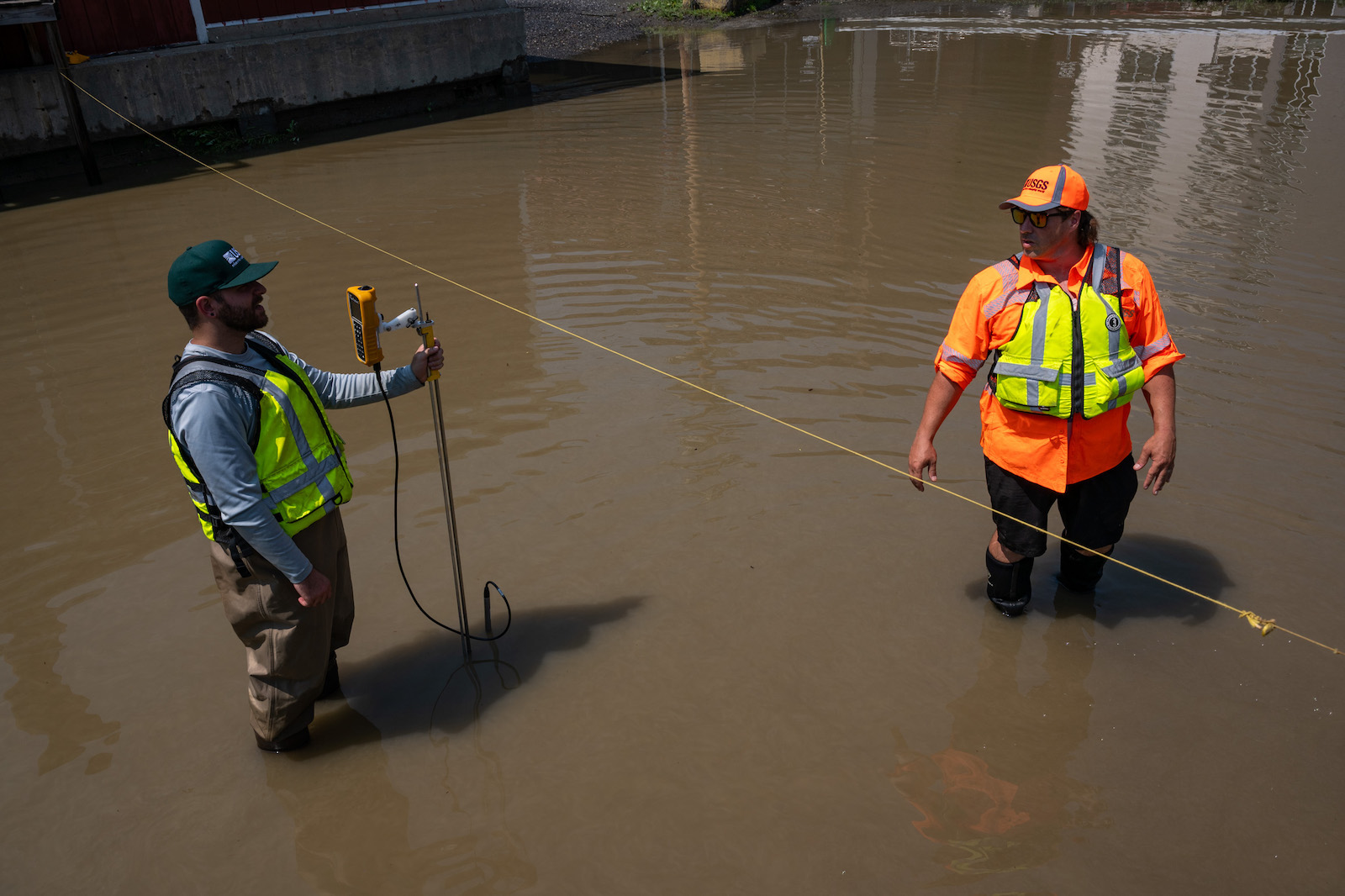 two people in construction vests in a brown river