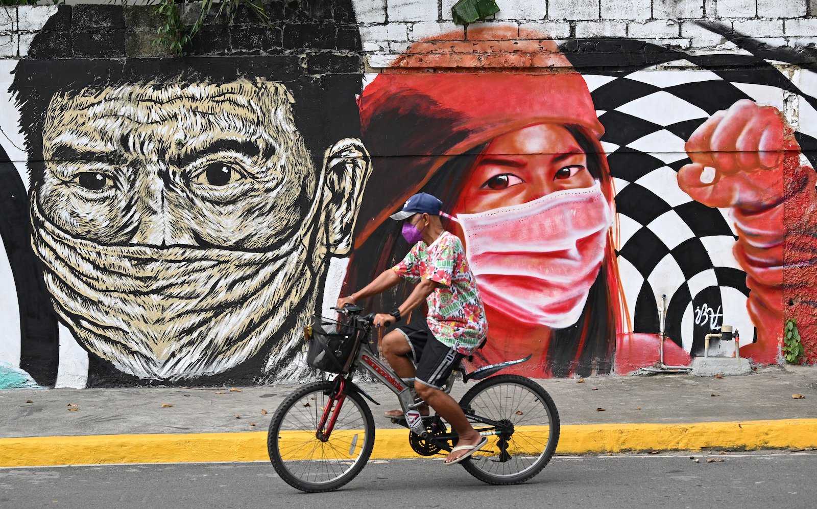 a mural with people in masks and a bike rider in front