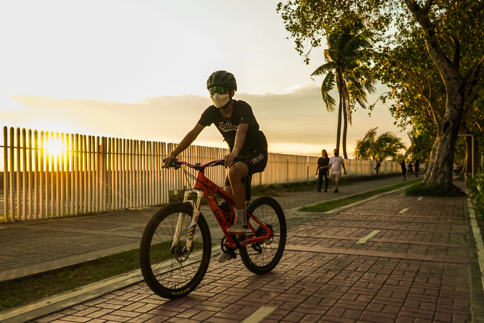 a person in a t-shire and shorts rides a bike at sunset on a paved street