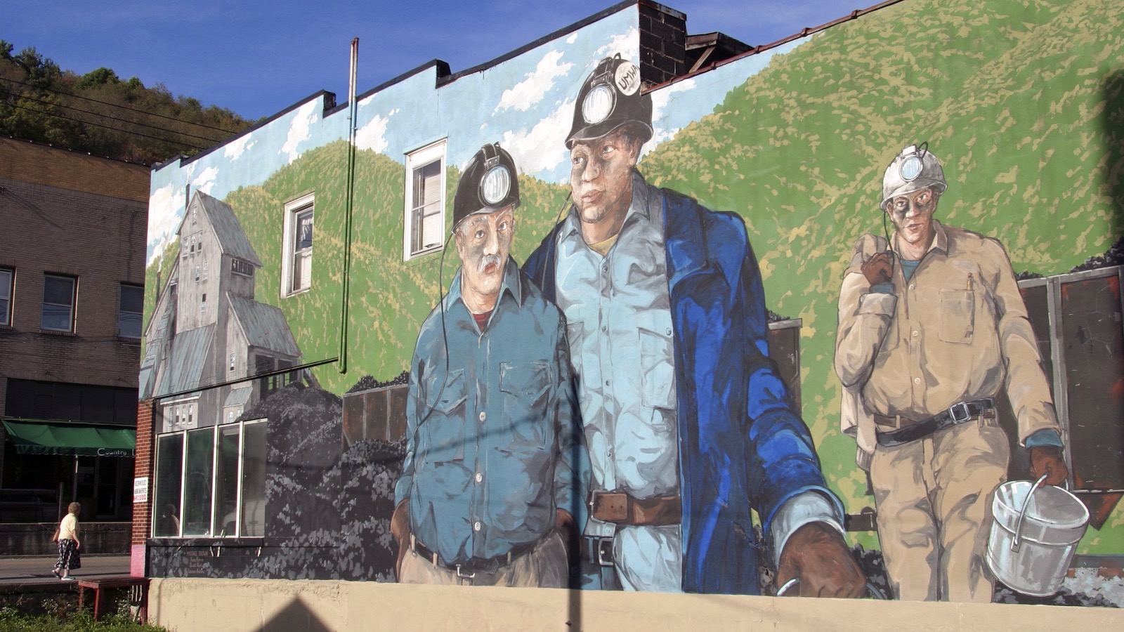 A mural depicting three coal miners is seen on the side of a building in rural West Virginia.