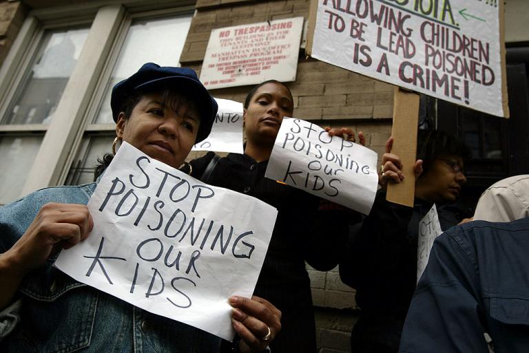 Parents with signs saying "stop poisoning our kids"