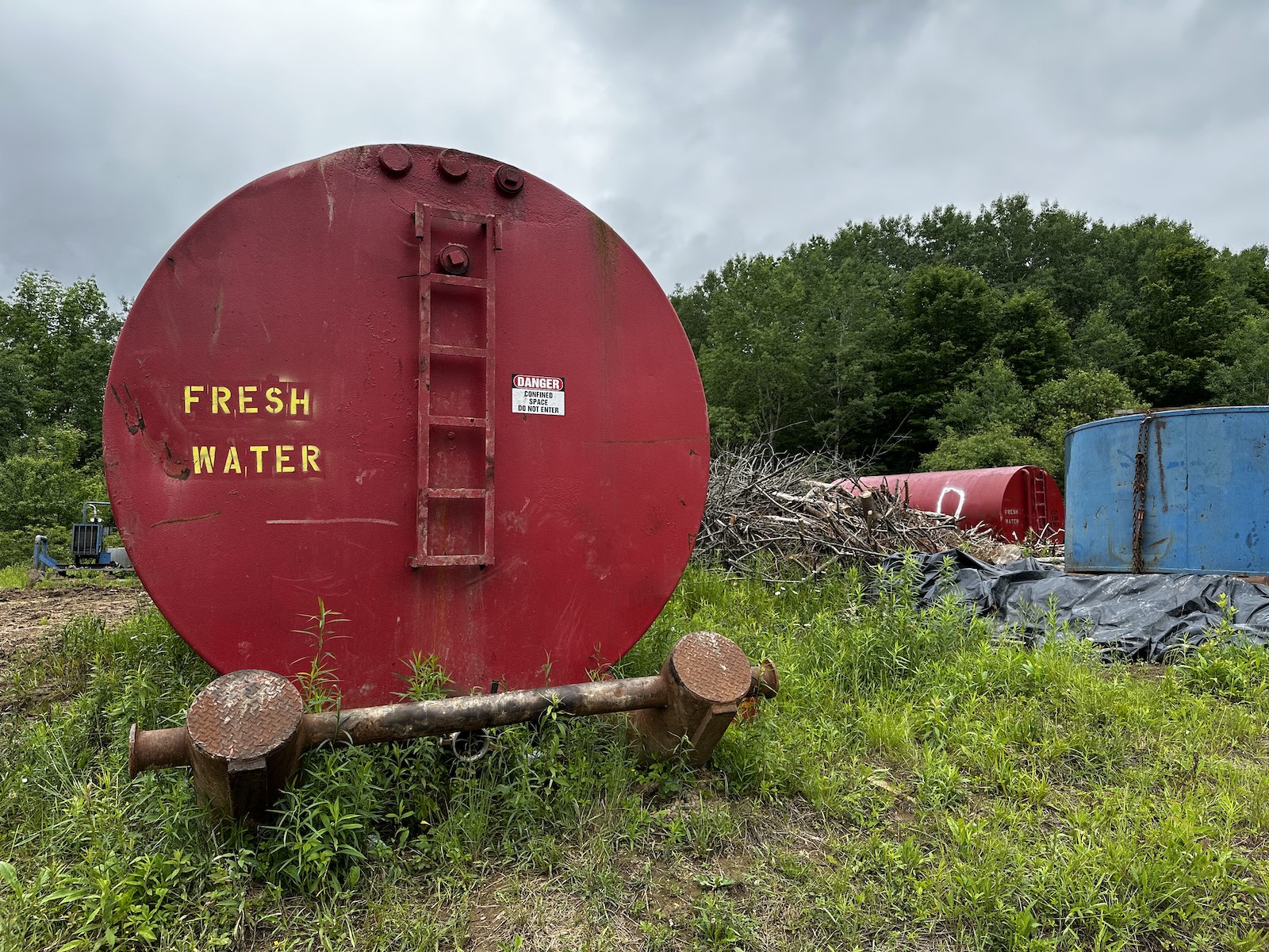 A large red container for holding water pulled from abandoned oil wells