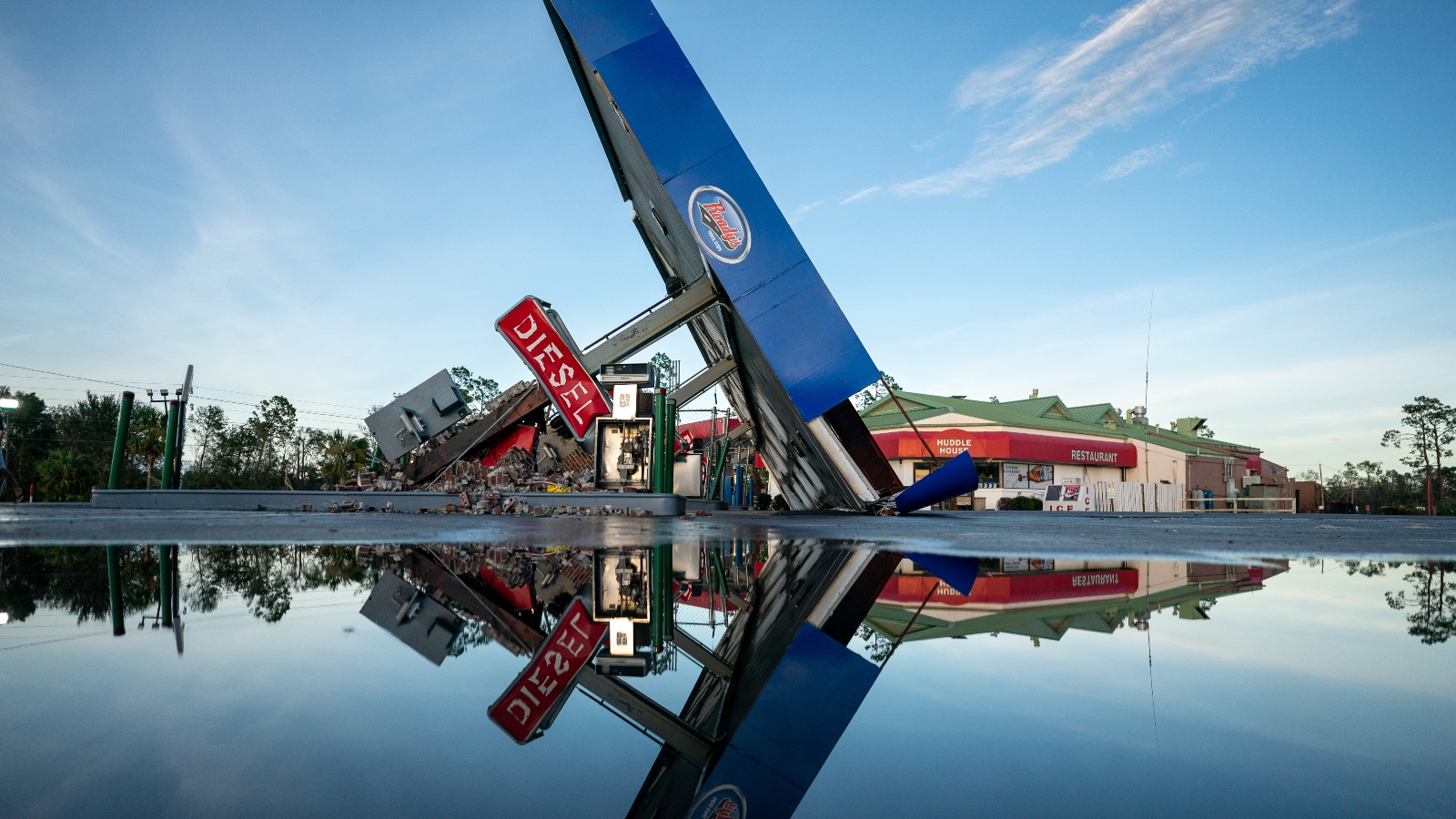 A storm-damaged gas station is reflected in a puddle after Hurricane Idalia passed over Perry, Florida on August 30, 2023.