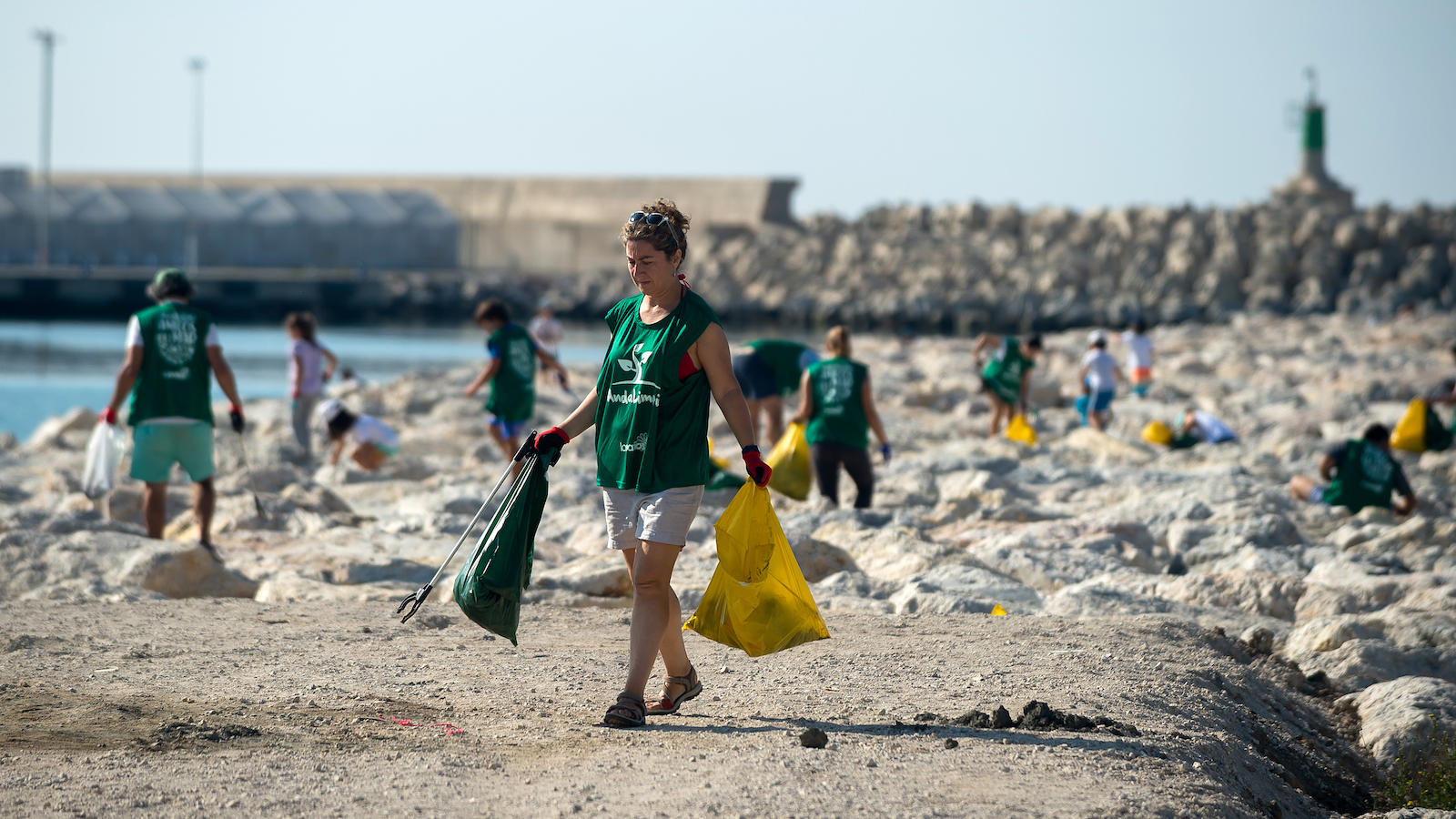 a woman holds trash bags of plastic on the beach