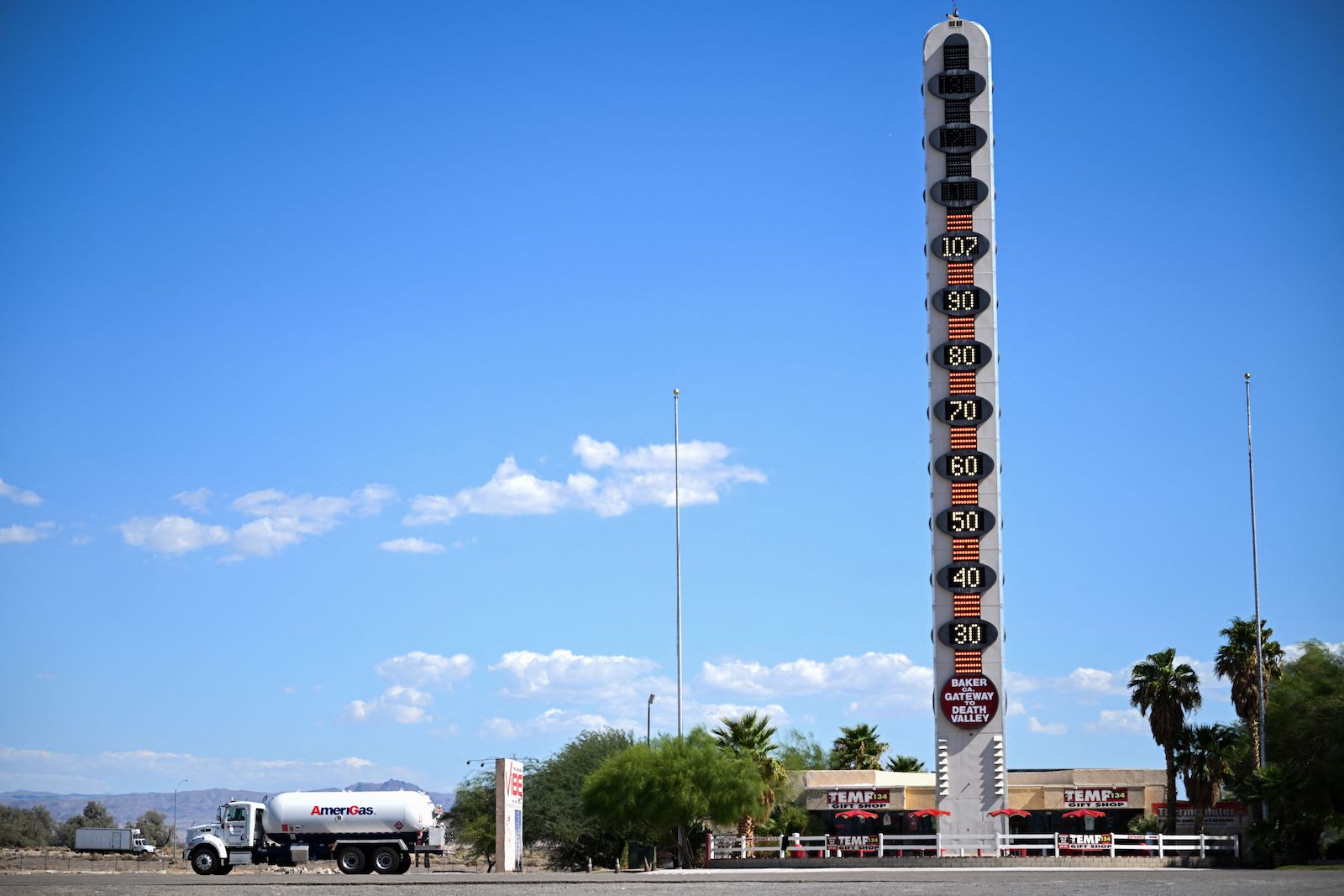 a very large thermometer roadside attraction next to a gas tanker