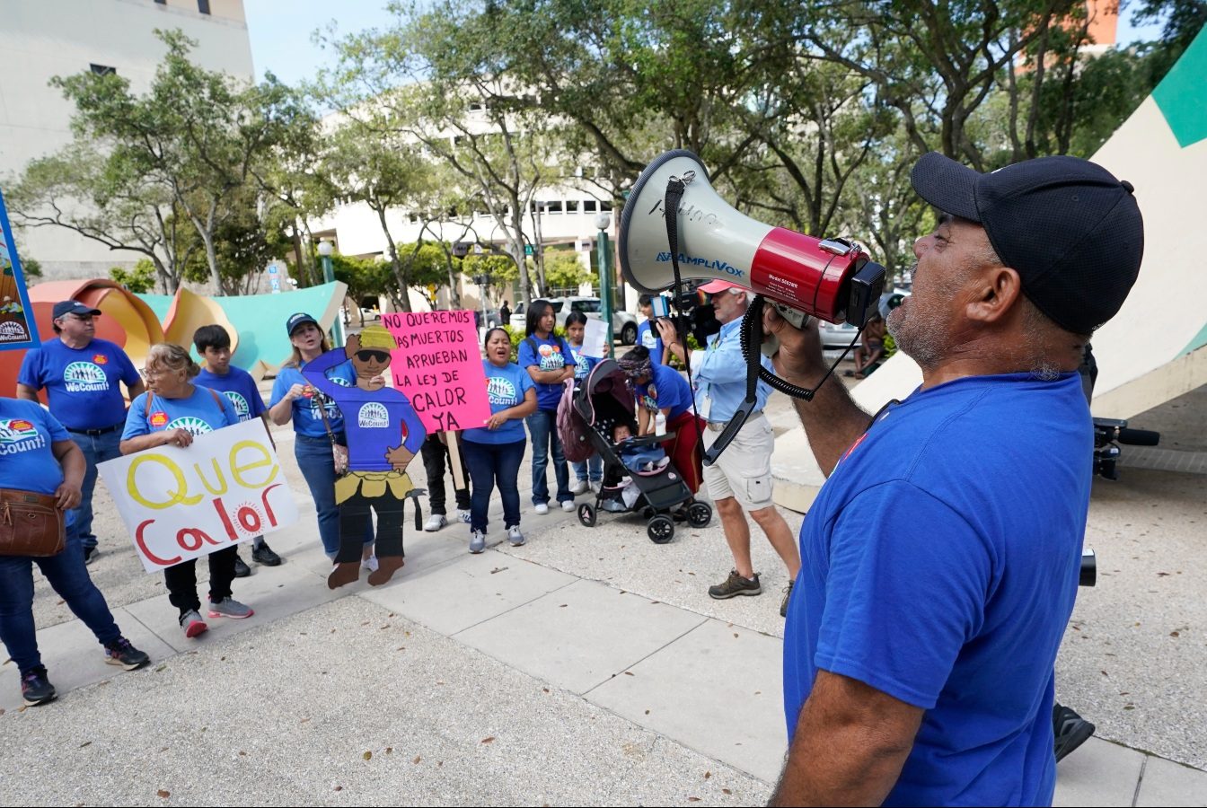 A man with a megaphone speaks to a small group of protesters